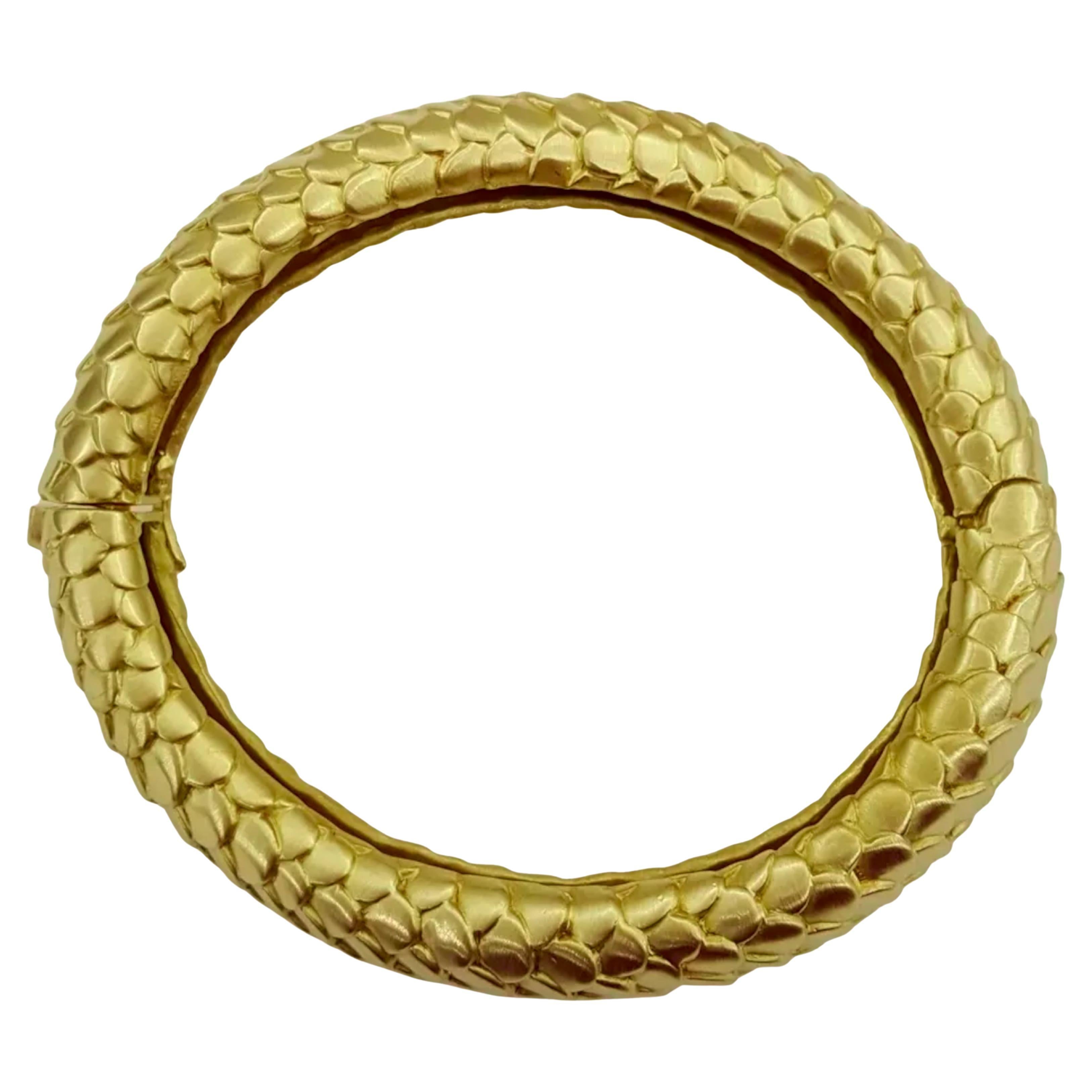 This Angela Cummings 18k yellow gold bangle bracelet is a striking piece of jewelry.  Its substantial weight and dimensions—a generous length to fit a medium wrist, and considerable width and thickness—give it a commanding presence. The distinctive