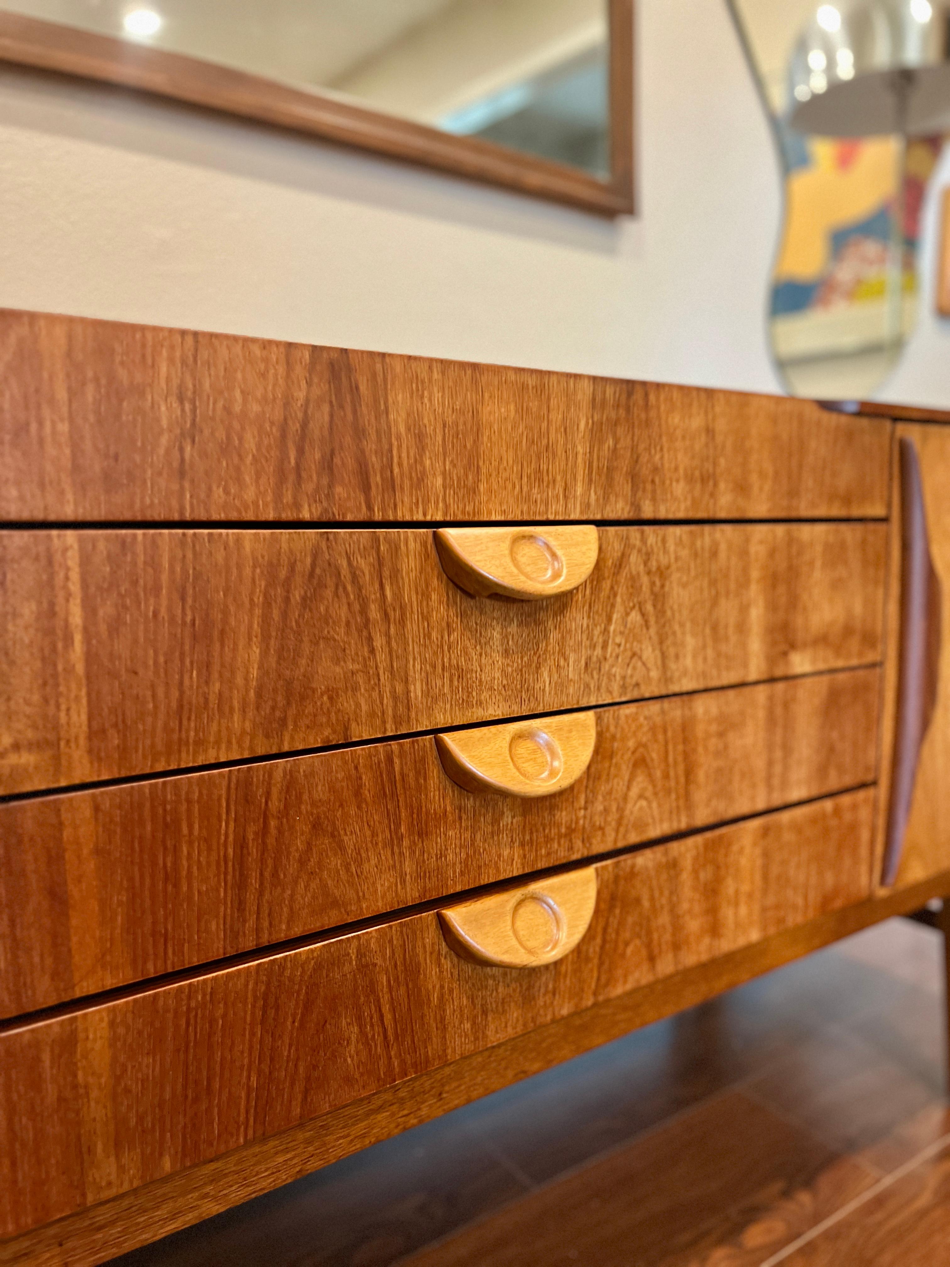 This beautiful mid century modern sideboard was designed by Beautility, circa 1960s. The sideboard features two spacious cupboards and three drawers. Beautility is renowned for its seamless and sleek design coupled with superbly high manufacturing