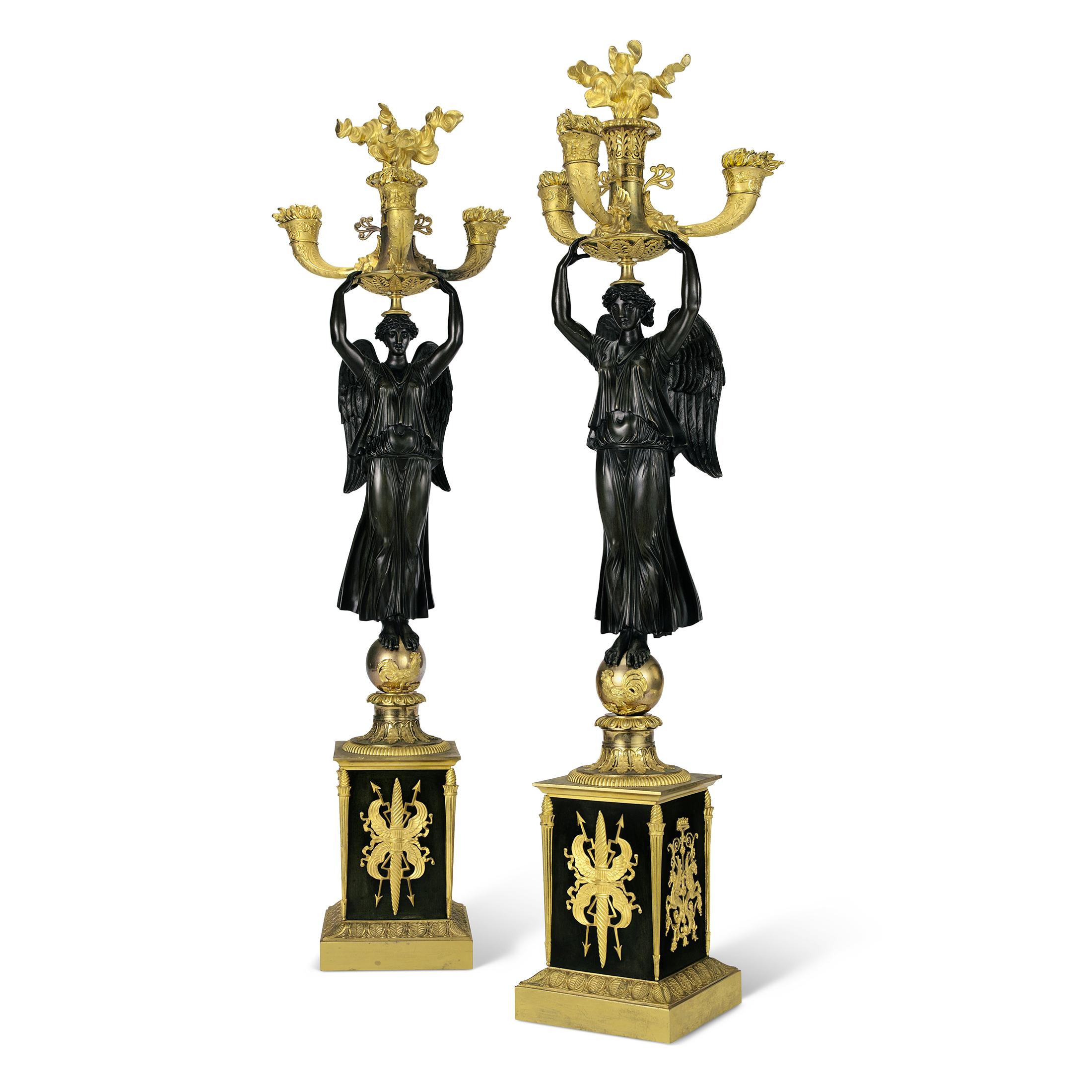     This exquisite pair of Empire four light Candelabras with winged maiden standing on a globe with a rooster mount surmounted on a square bases are fabulous pair! Burning cornucopias form the four candleholders on each candelabra, surmounted by a