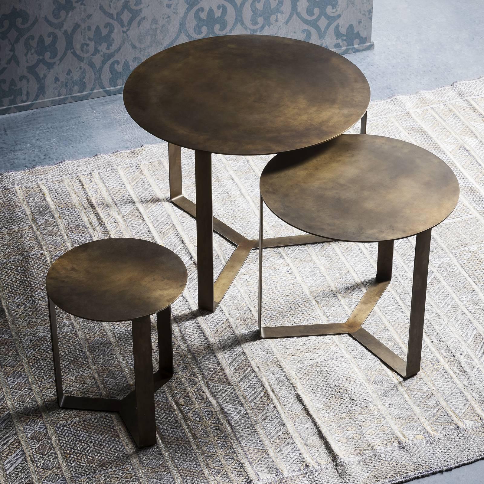 This stackable coffee-table is rendered using laser-cut metal. The streamlined Silhouette features a round tabletop supported by three legs arranged in a pinwheel formation connected at a central point. The hand-applied, engraved, non-toxic resin