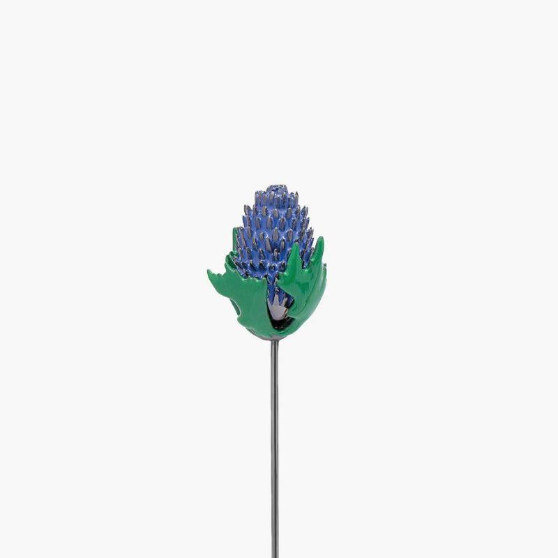 Thistle pin with enamel and matte black rhodium finish

Conveying the texture and shape of a thistle, set in a black rhodium plated base metal stem with purple and green-coloured enamel for the leaf and petal elements. A highly-polished finish