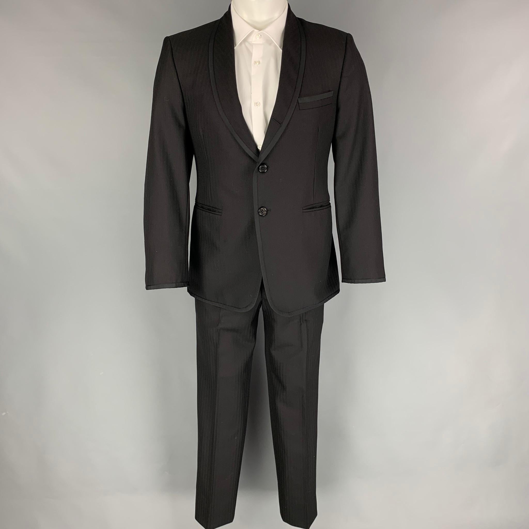 THOM BROWNE for NEIMAN MARCUS tuxedo suit comes in a black on black herringbone material with a full liner and includes a single breasted, three button sport coat with a shawl lapel and matching pleated front trousers. Handmade in USA.

Excellent
