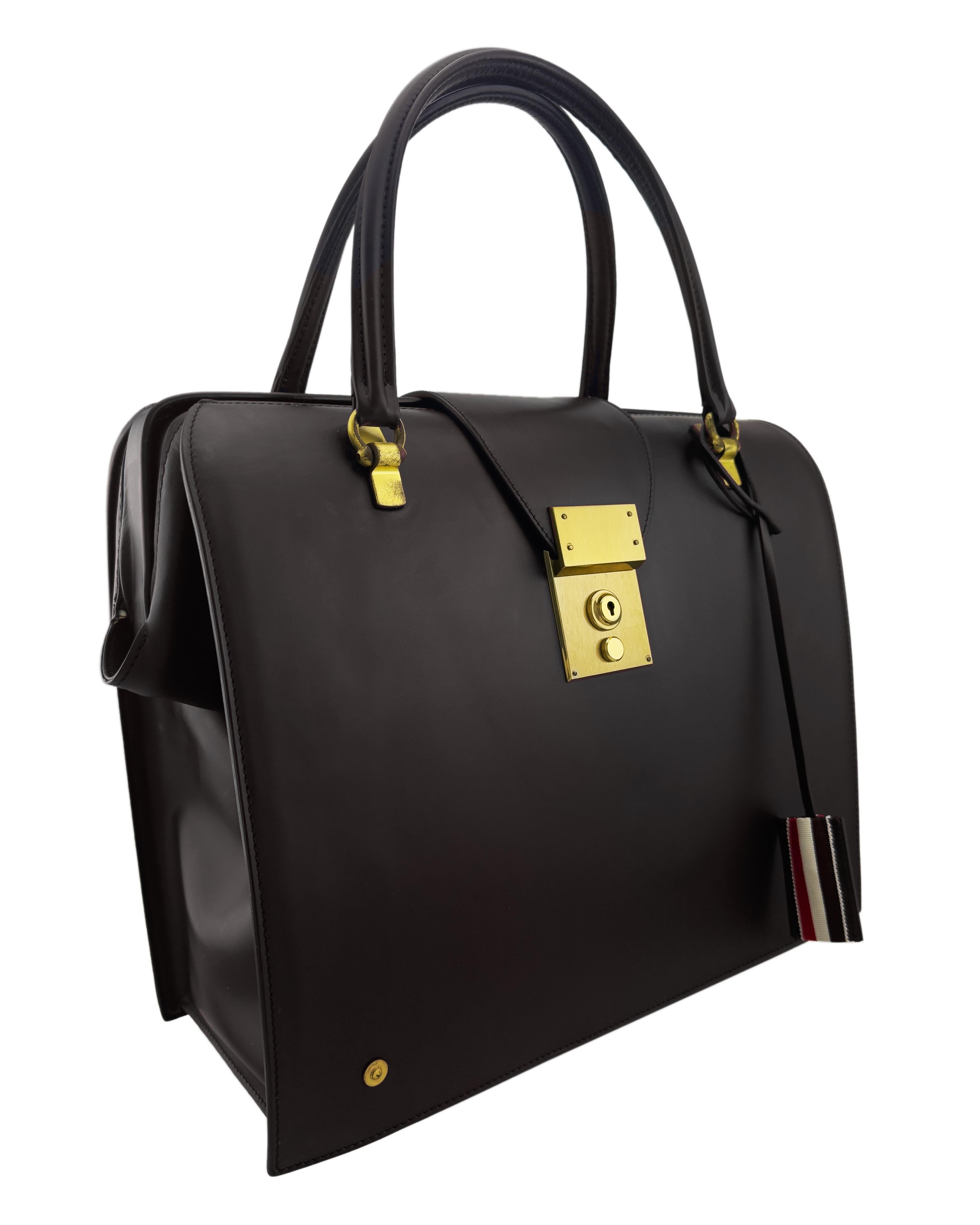 Mr. Thom Bag in smooth dark brown leather. Dating back to the origins of Thom Browne, an iconic silhouette, championing signature detailing such as a striped leather key holder and gold foil logos.

Brass lock closure at front
Rounded leather top