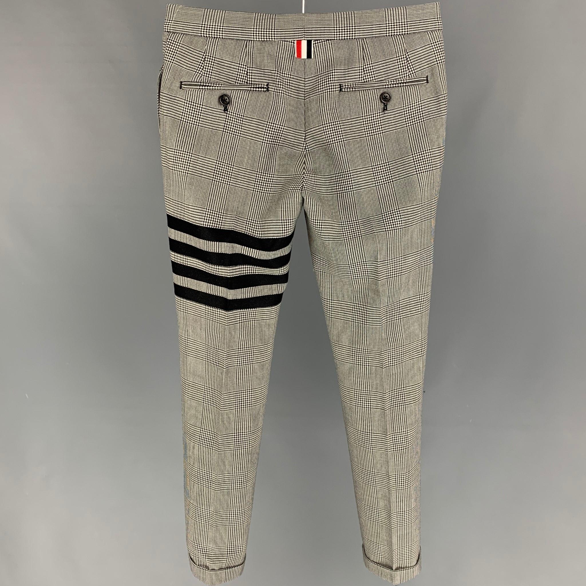THOM BROWNE dress pants comes in a black & white glen plaid wool featuring a tapered leg, cuffed, stripe trim design, signature stripe details, front tab, and a button fly. Made in Italy. 

Excellent Pre-Owned Condition.
Marked: 36
Original Retail