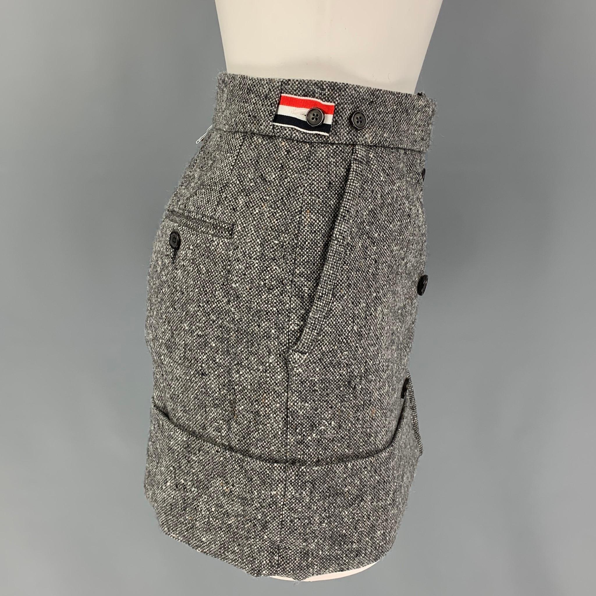 THOM BROWNE mini skirt comes in a grey mohair / merino wool featuring a cuffed hem, signature striped trim,  side tabs, back pockets, and a front double breasted closure. Made in Italy. 

Excellent Pre-Owned Condition.
Marked: 36
Original Retail
