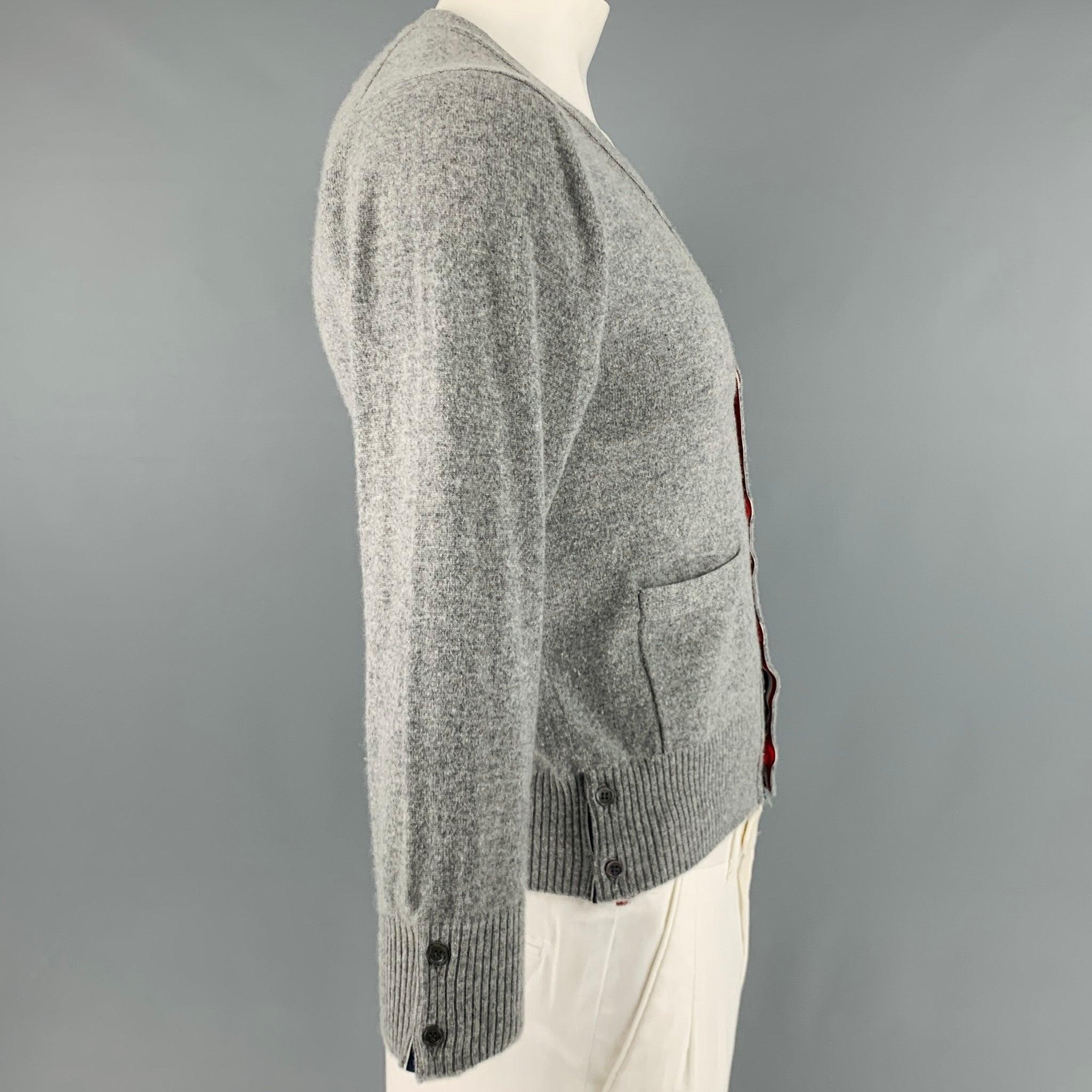 THOM BROWNE cardigan
in a grey cashmere knit featuring cream stripe arm detail, signature contrast button trim, button cuffs and hem, and button closure. Made in Italy.Very Good Pre-Owned Condition. Moderate pilling on sides and under arms.