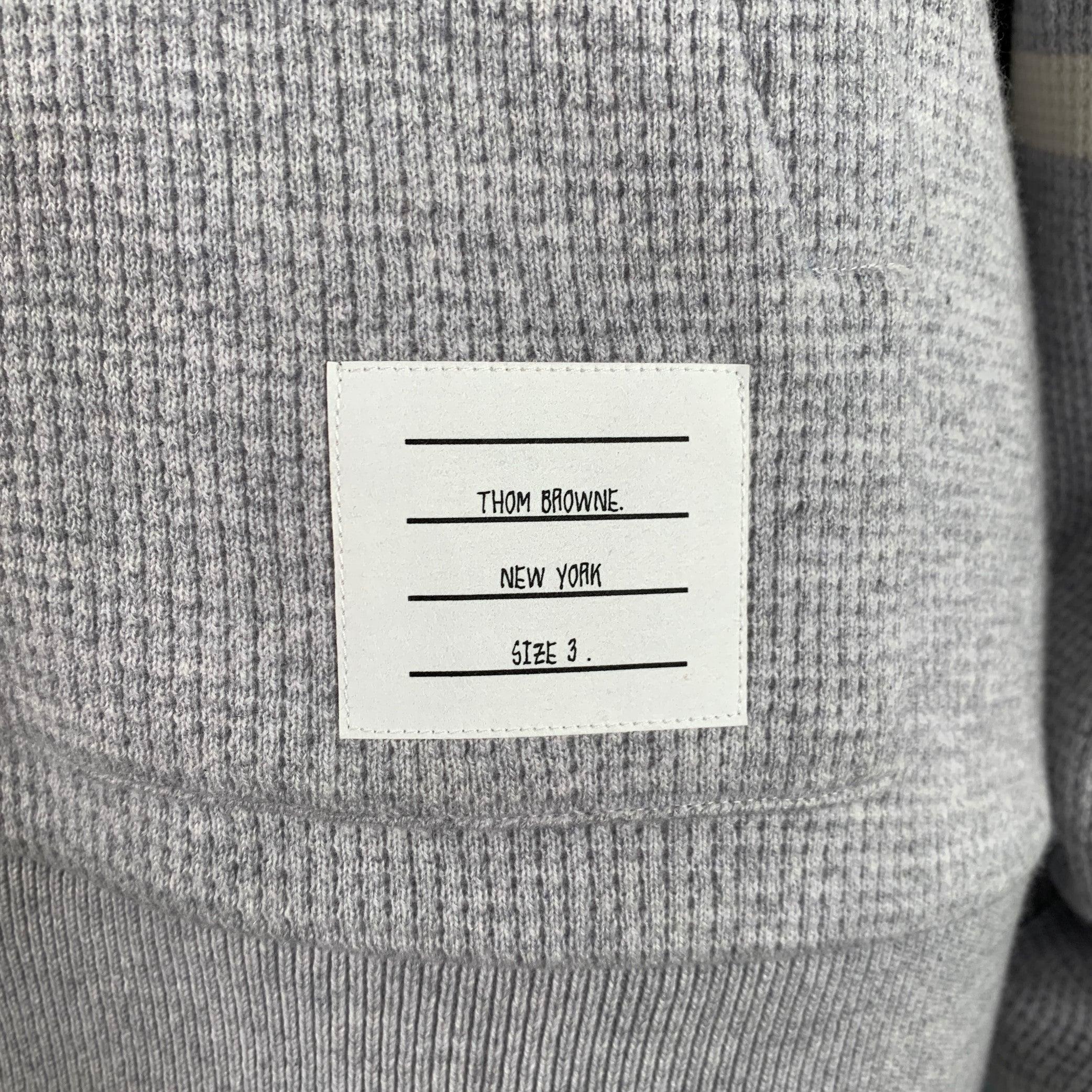THOM BROWNE casual top
in a grey cashmere wool waffle knit featuring a hooded style, signature cream stripe details, and kangaroo pocket. Made in Italy.Very Good Pre-Owned Condition. Minor mark on back of right sleeve. 

Marked:   3 

Measurements: