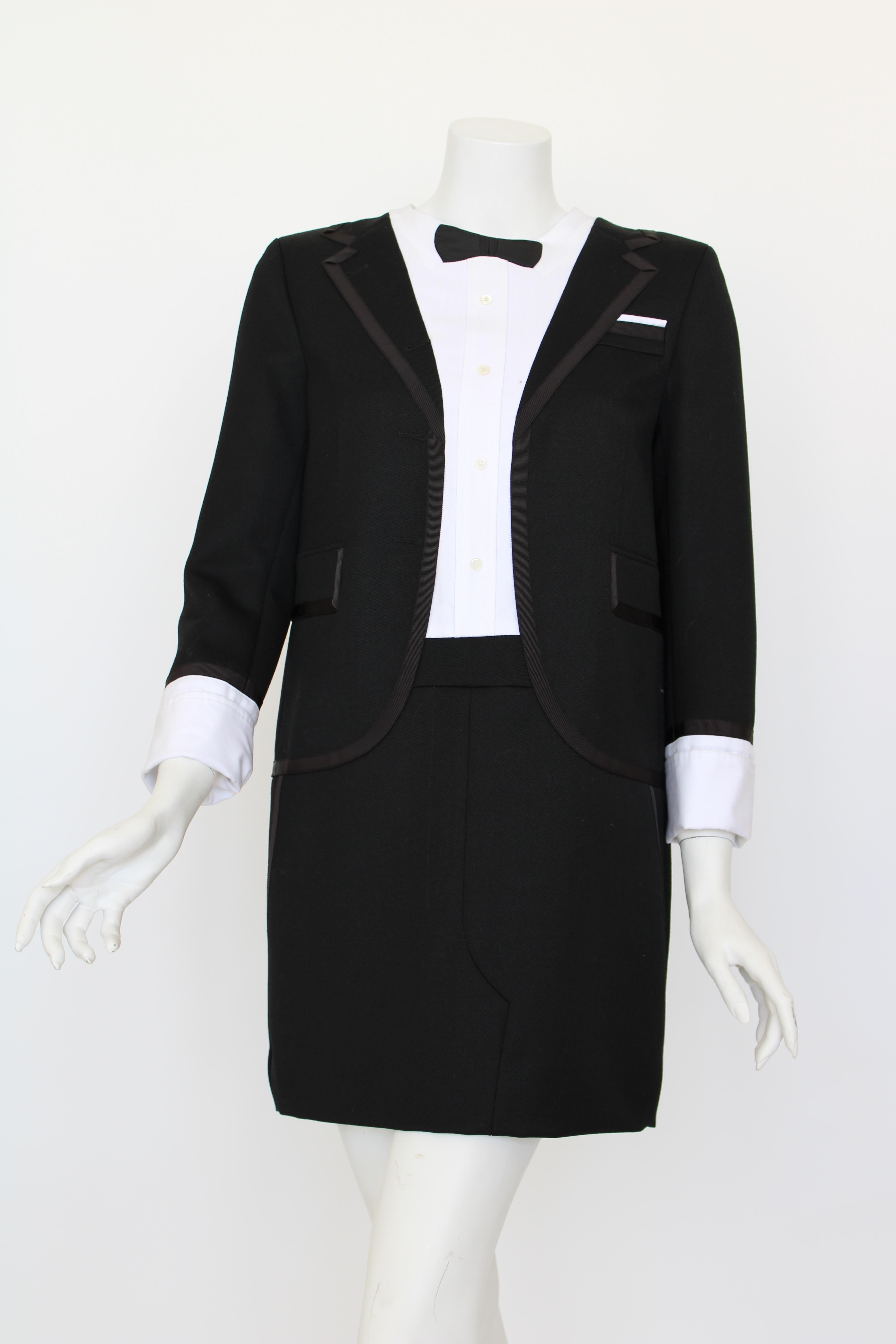Black/white wool-cotton-silk blend tuxedo-style mini dress from Thom Browne featuring round neck, signature grosgrain loop tab, RWB stripe, long sleeves, buttoned cuffs and a tuxedo style. 