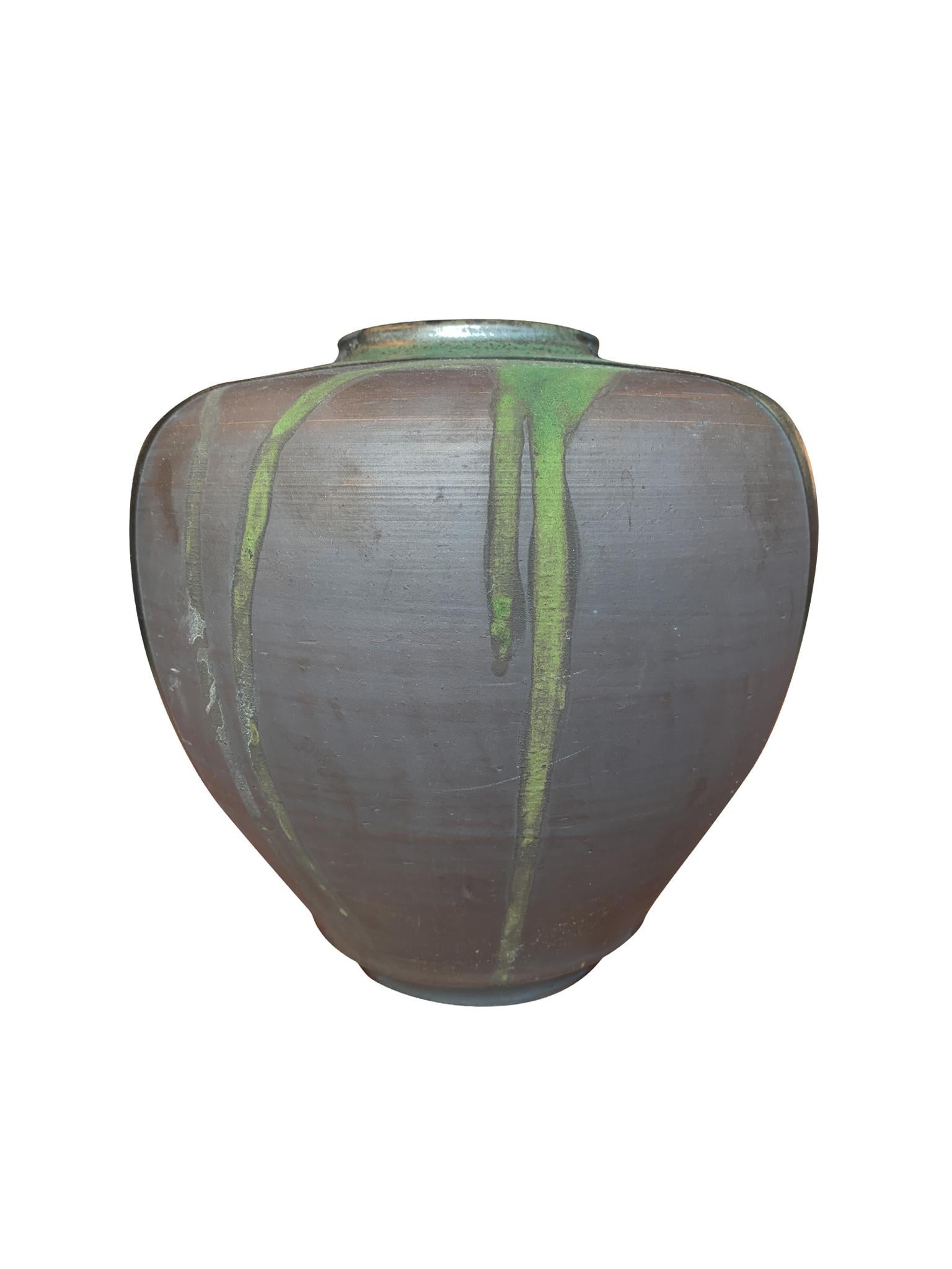 A Thom Lussier ceramic vase with a rotund shape. The vase is one of a series of vessels on which the artist applies a mixture of glazing techniques to create richly textured surfaces. Here, he combines metallic glazing with a matte finish. The