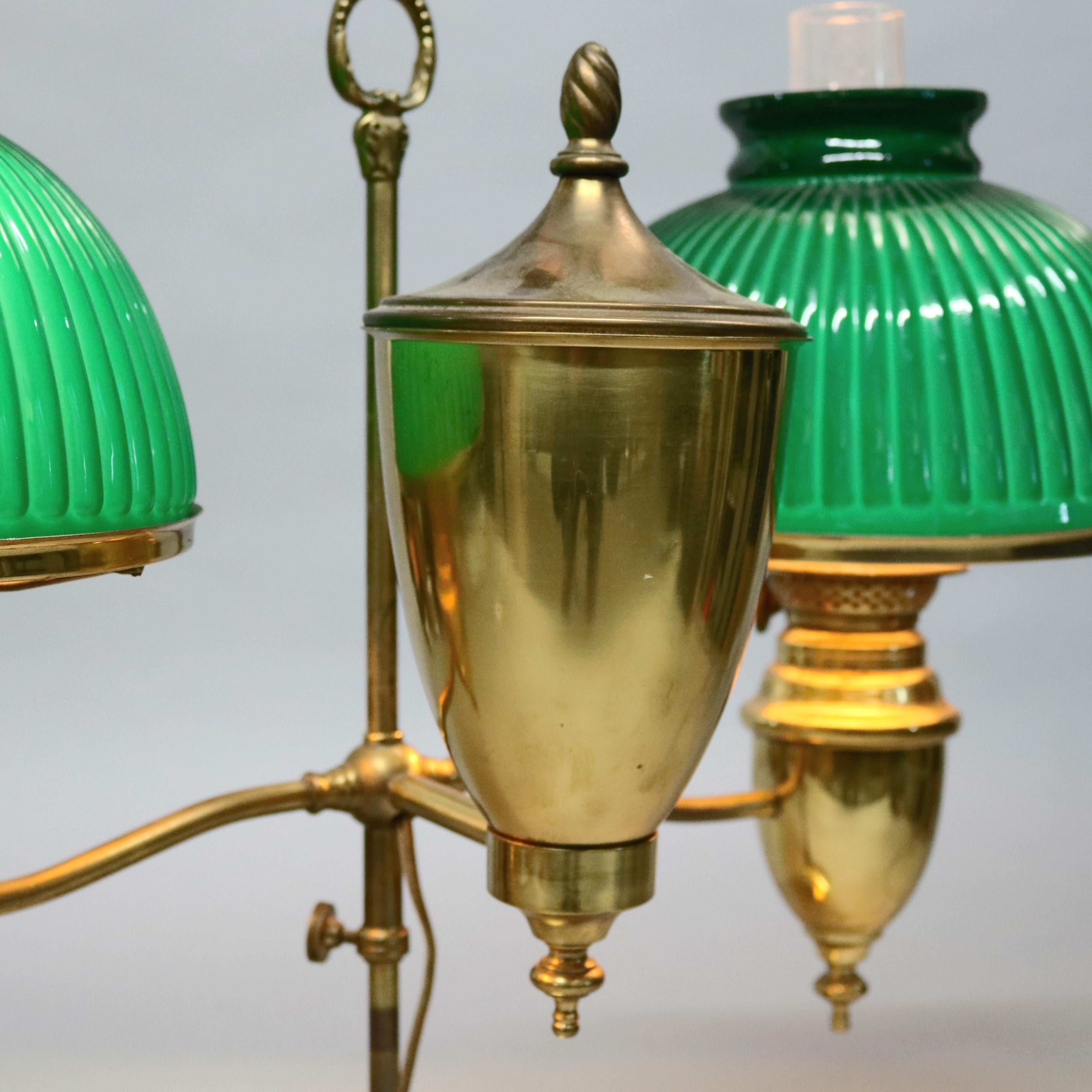 An antique Arts & Crafts double student lamp by Thomas Adams offers brass frame having urn form fonts and adjustable arms terminating in lights with cased glass shades, maker signed burner, circa 1940.

Measures- 20.25