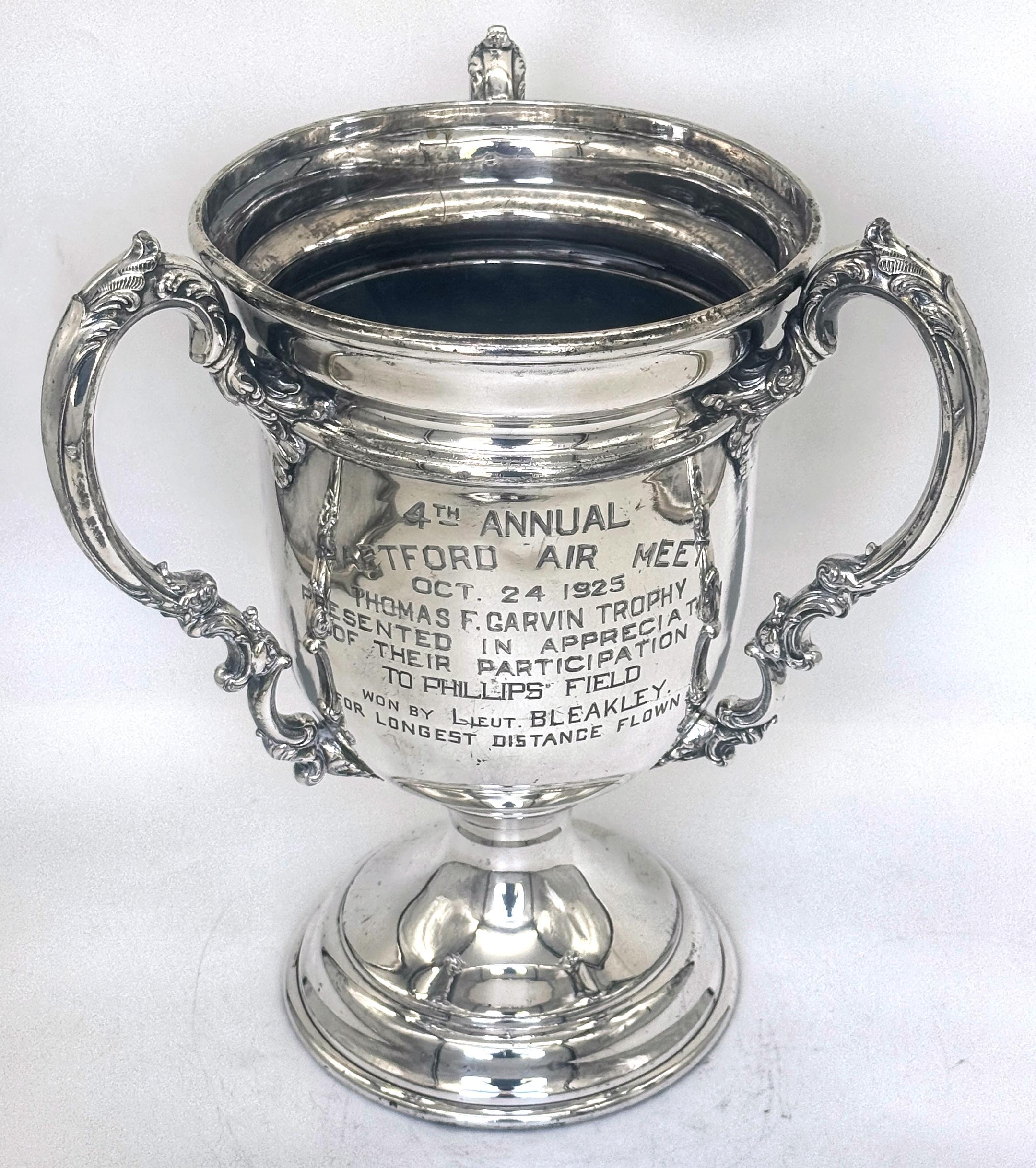 Thomas F. Garvin-Trophäe, 1925 Aviation-Trophäe, von Wilcox Silver Plate Co.

Diese versilberte Trophäe ist etwa 14 Zoll hoch, 11 Zoll breit und 11 Zoll tief und stellt ein bemerkenswertes Stück früher Luftfahrtgeschichte dar. Gepunzt mit der Wilcox