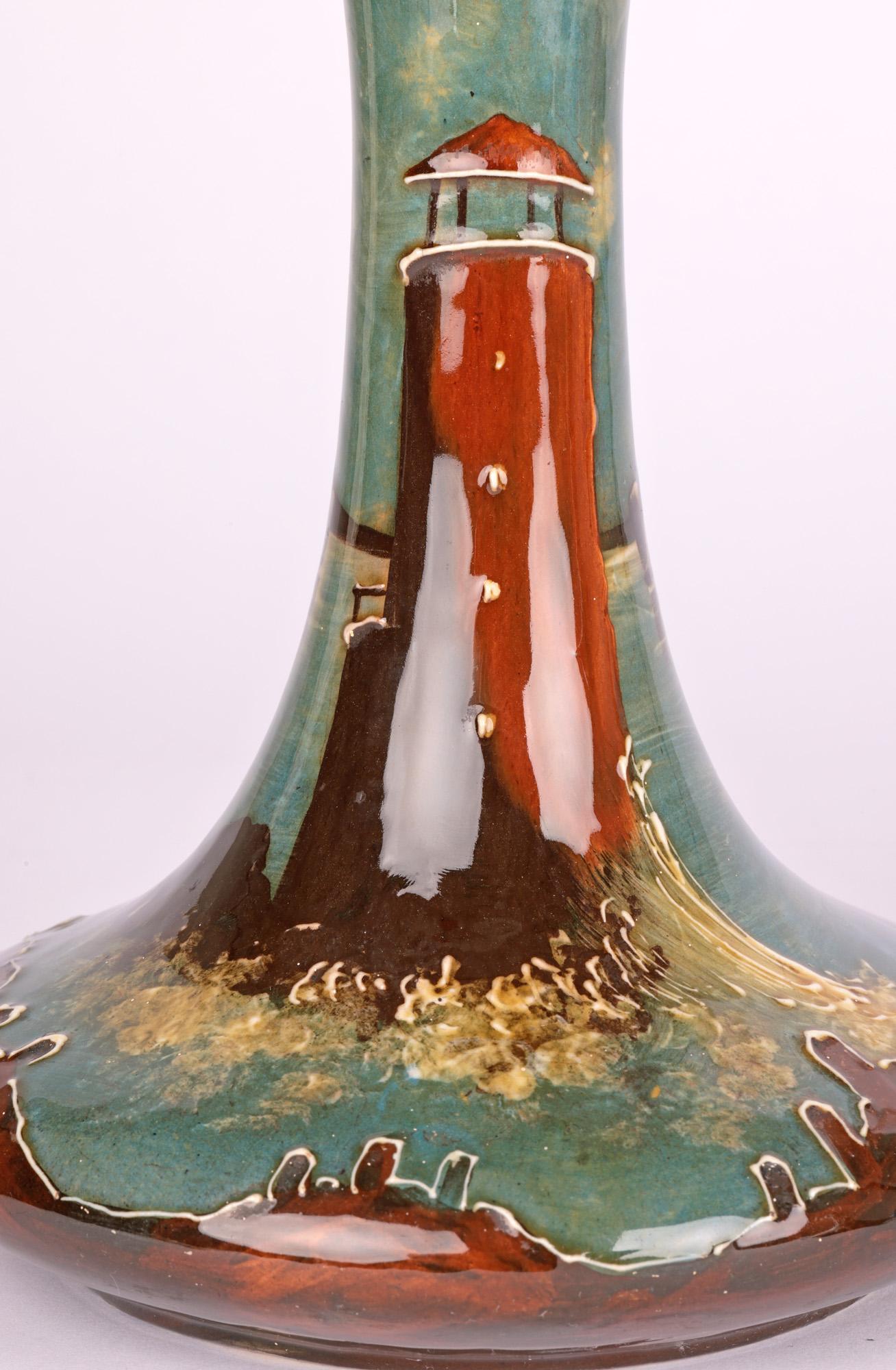 A rare and unusual pair art nouveau pottery vases hand painted with lighthouses attributed to Thomas Forester and dating from around 1910. The vases are of carafe shape with a wide squat round body standing on a narrow round unglazed foot with