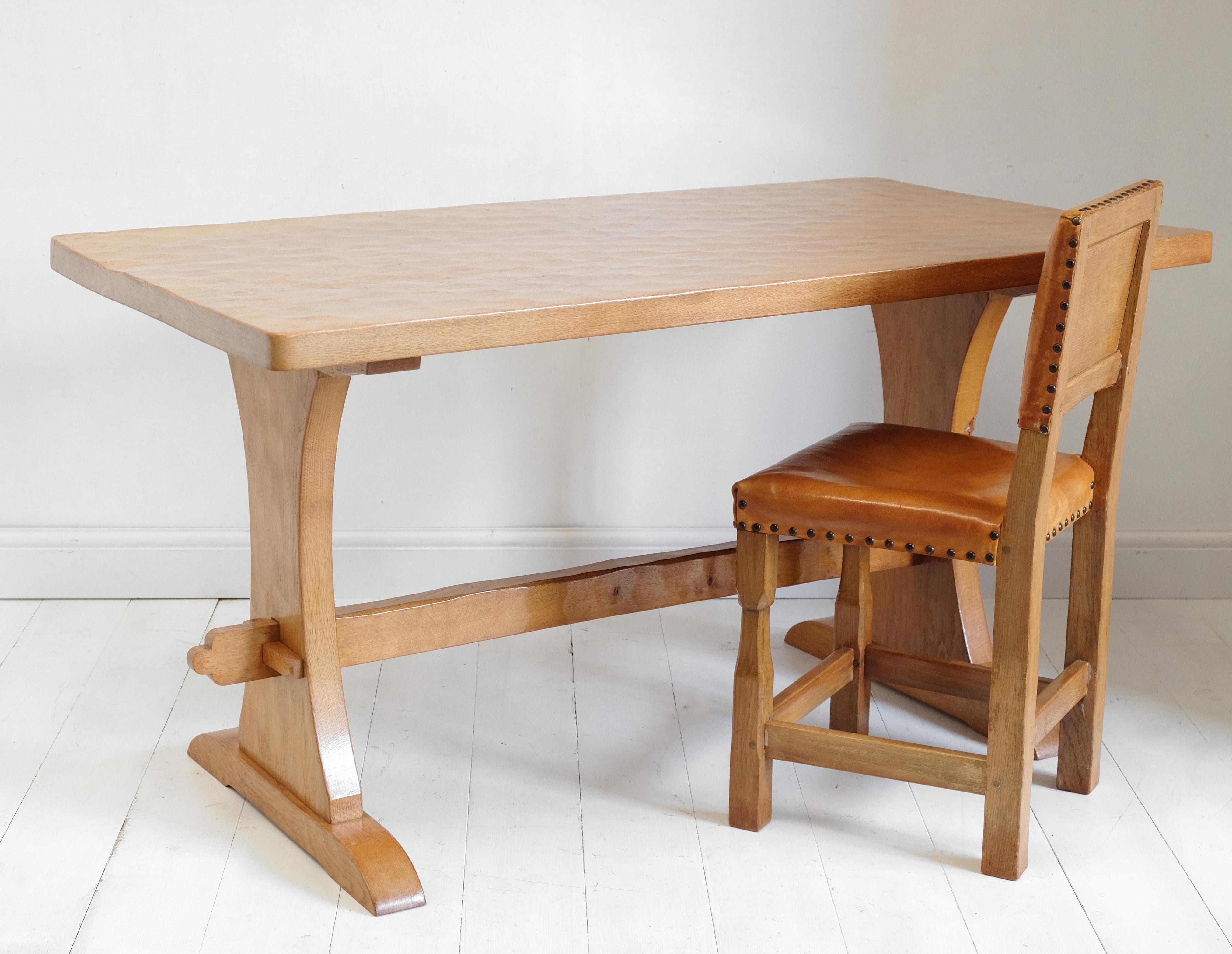 A complete dining set in solid oak by Thomas Whittaker of Littlebeck, aka Gnomeman. The set features a trestle ended table, a rare bench with shaped backrest, two rare carvers and two dining chairs. The surfaces of the table and bench and the backs