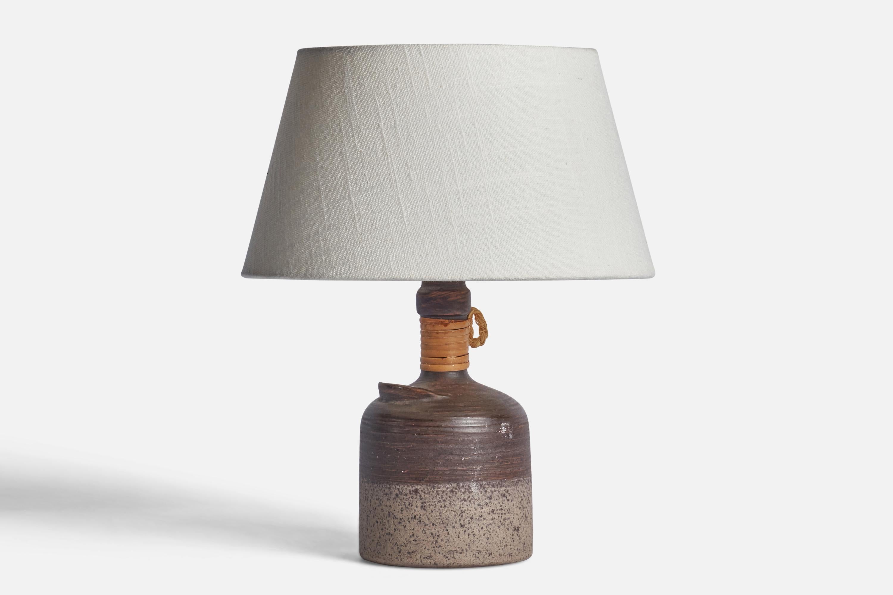A grey-glazed incised ceramic, rattan and cord table lamp designed by Thomas Hellström and produced by Nittsjö, Sweden, c. 1970s.

Dimensions of Lamp (inches): 9” H x 4.25” Diameter
Dimensions of Shade (inches): 2.5” Top Diameter x 10” Bottom