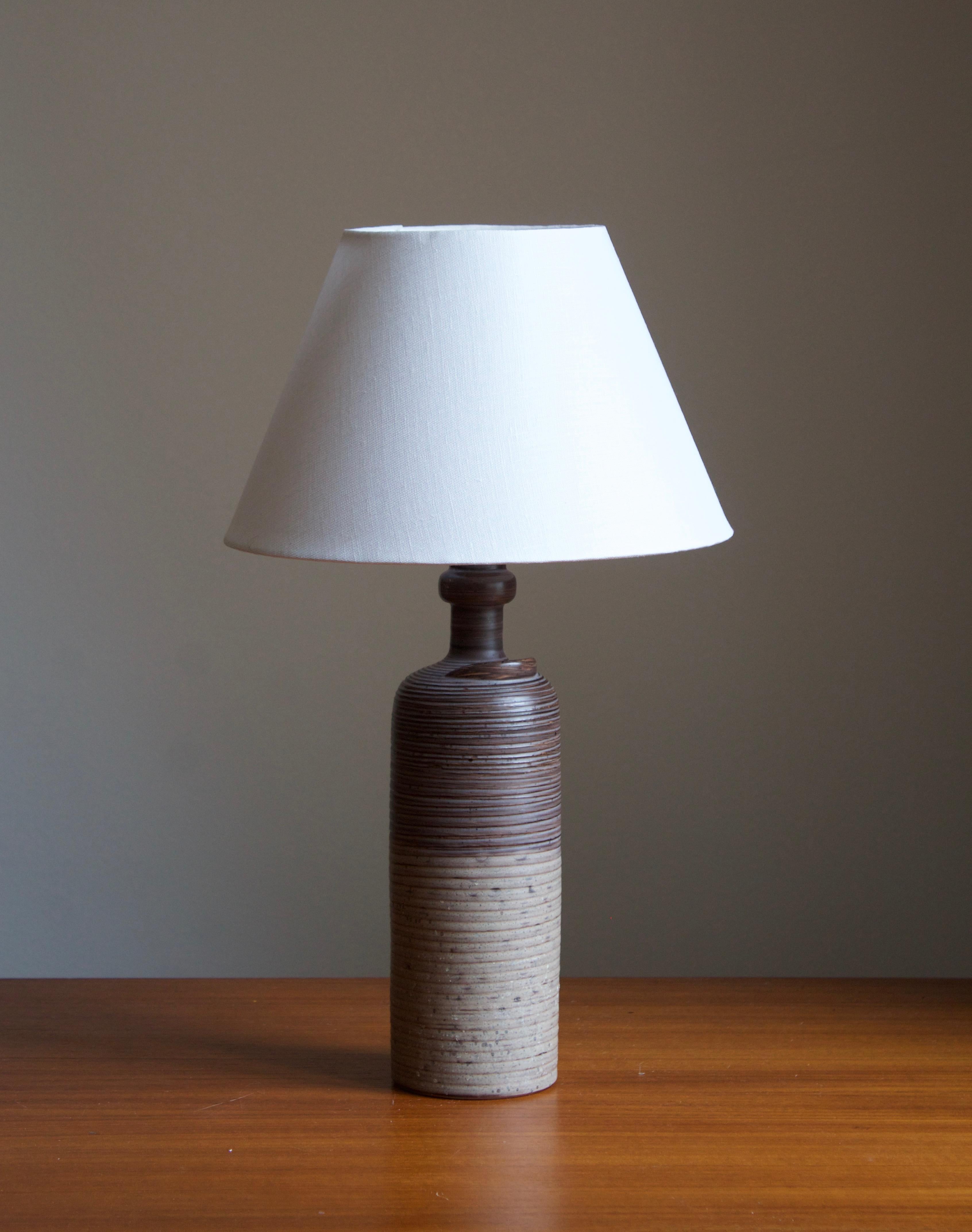 A table lamp designed by Thomas Hellström, produced by Nittsjö, Sweden, c. 1960s.

Features subtle incised decor and a sculptural detail.

Stated dimensions exclude lampshade. Height includes socket. Sold without lampshade.

Glaze features