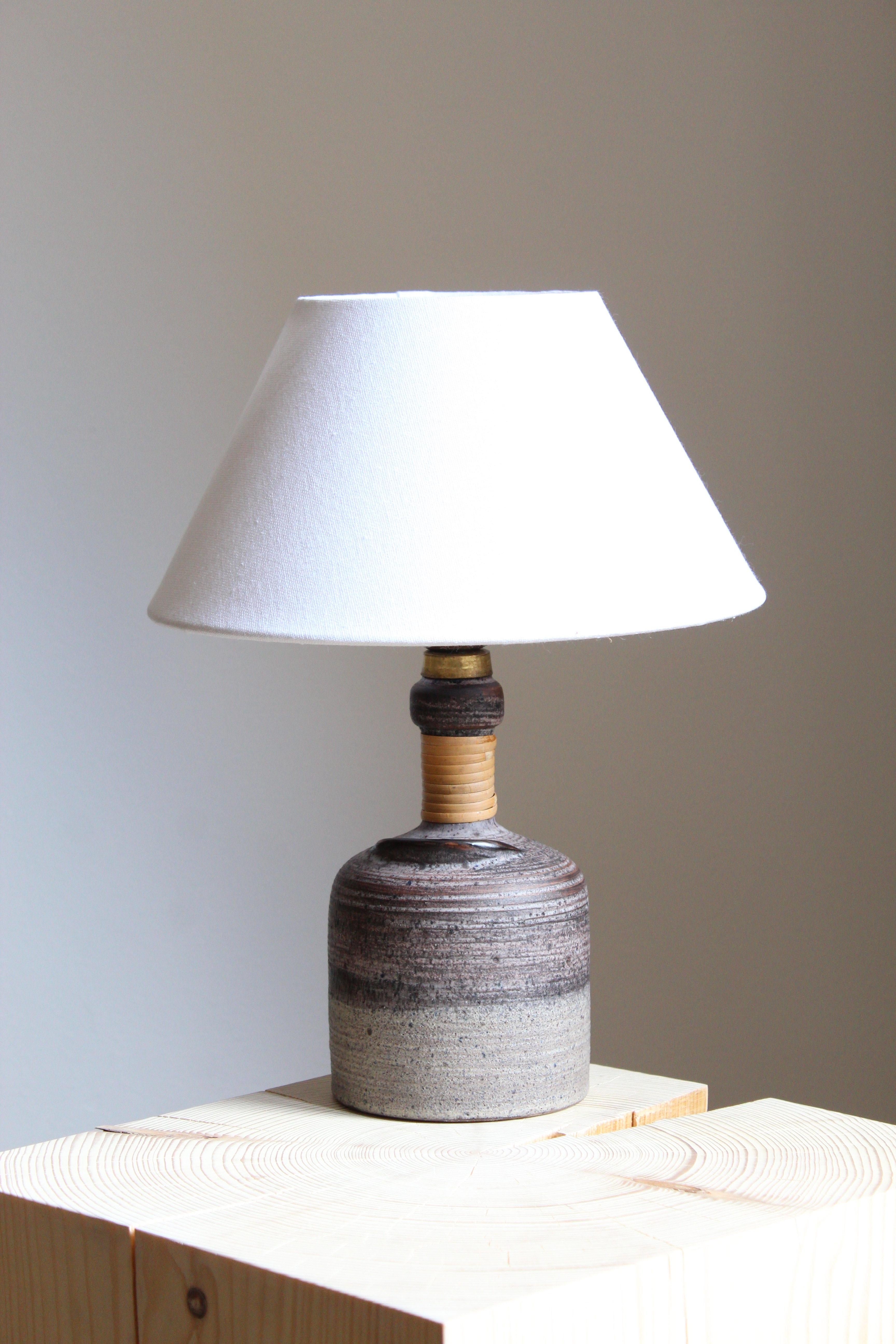 A table lamp designed by Thomas Hellström, produced by Nittsjö, Sweden, c. 1960s.

Features subtle incised decor and a sculptural detail as well as original cane wrapping.

Stated dimensions exclude lampshade. Height includes socket. Sold without