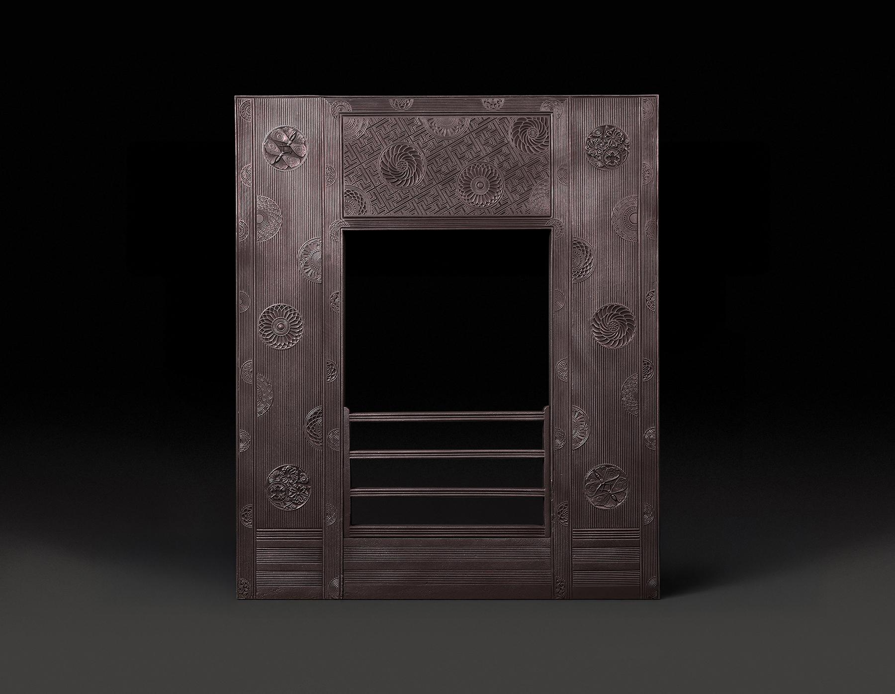 Griglia anteriore di una stufa a registro Thomas Jeckyll in ferro nero della fonderia Barnard, Bishop & Barnards. L'intera cornice con disegno floreale asimmetrico, i tondi con quattro api all'interno dei pannelli laterali e le tre barre di fuoco