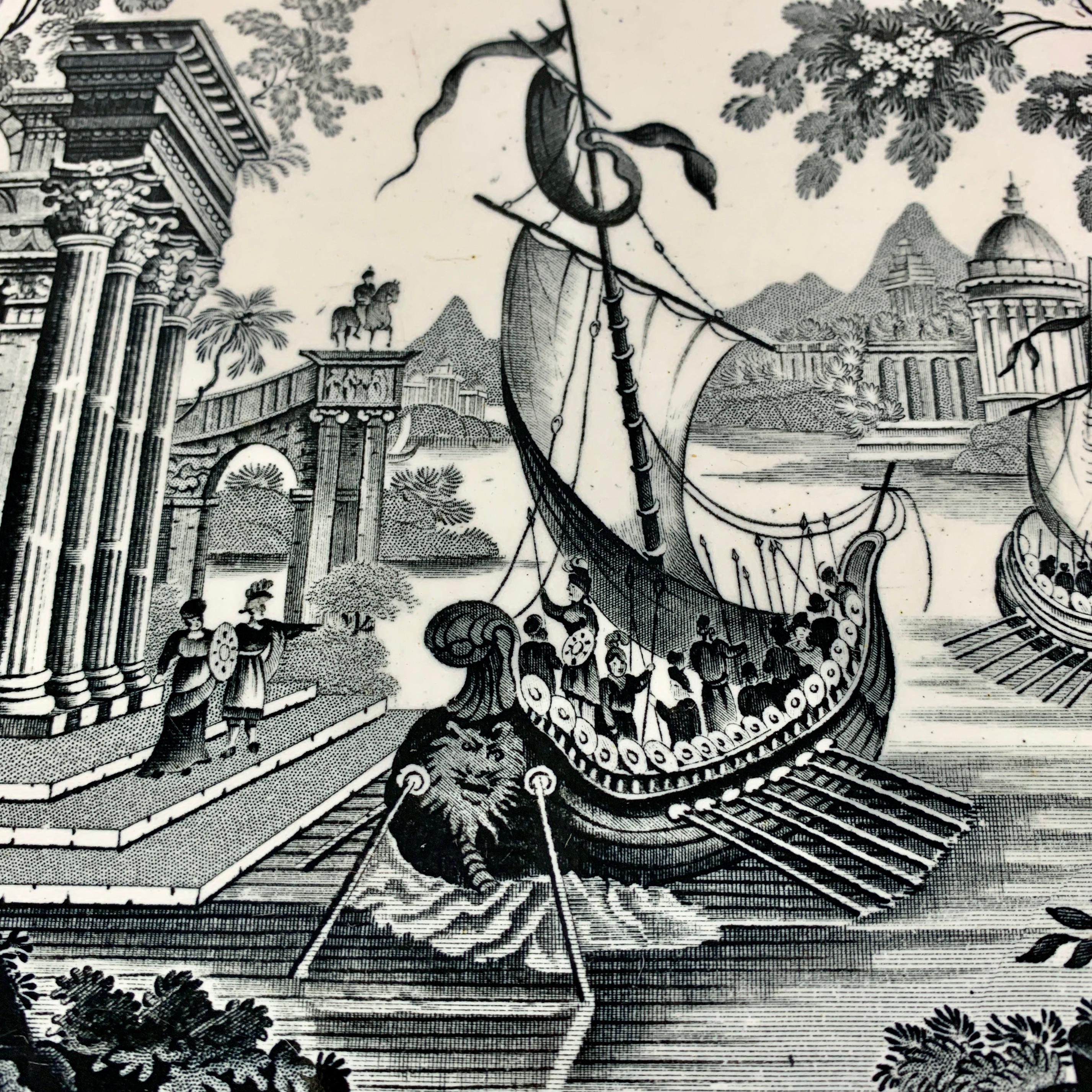 A transferware platter by Thomas Mayer, Stoke-on-Trent, Staffordshire, Circa 1826-1838.

From the Oriental Scenery series, a black transfer on a white earthenware body, showing exotic sailing vessels filled with oarsmen preparing to dock beside