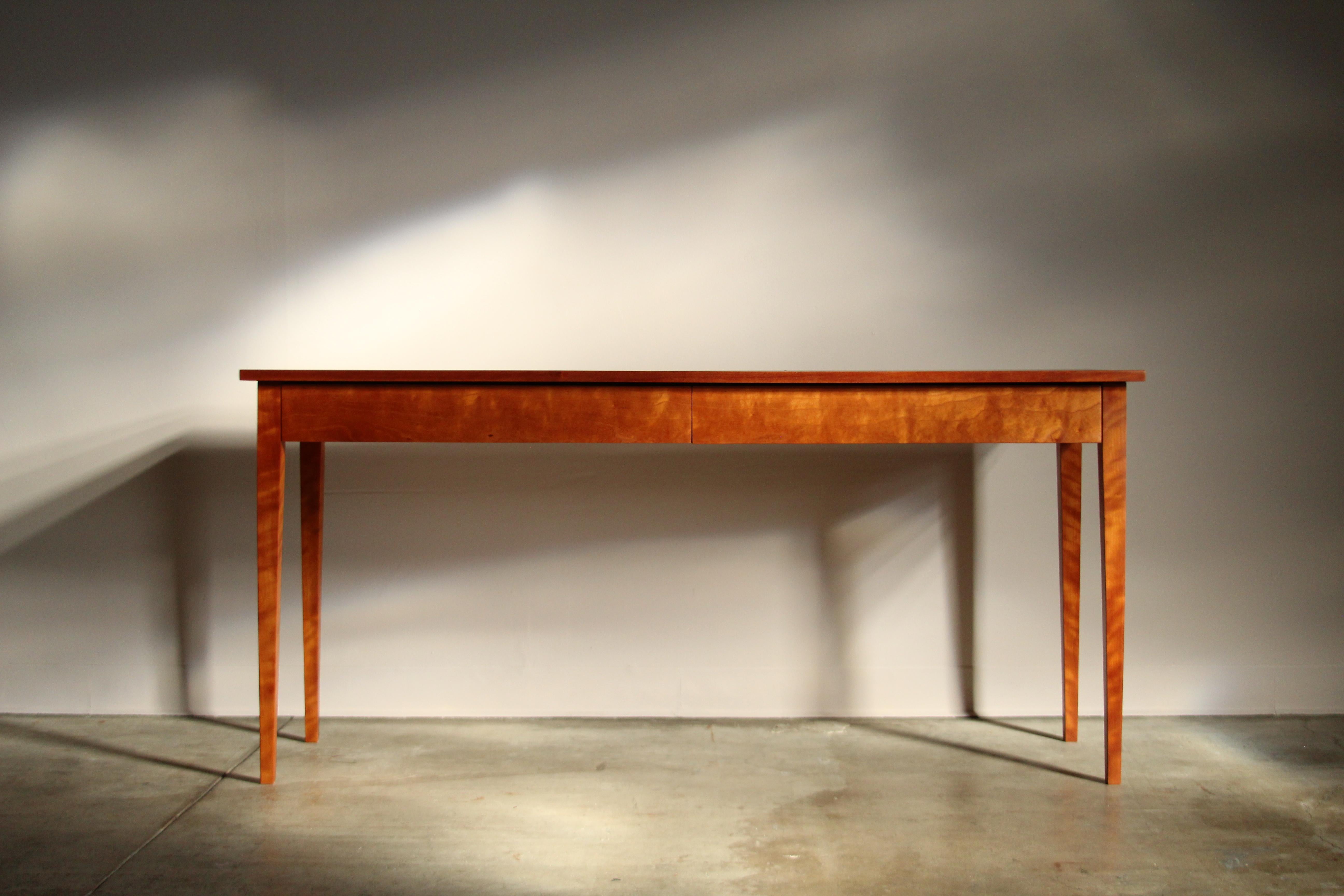 A vintage Shaker style console table by Thomas Moser, made in New Gloucester, Maine in 1983. Executed in solid cherry wood, this minimalistic piece features dovetail joinery, tapered legs, and clean, timeless lines. Two concealed drawers allow for