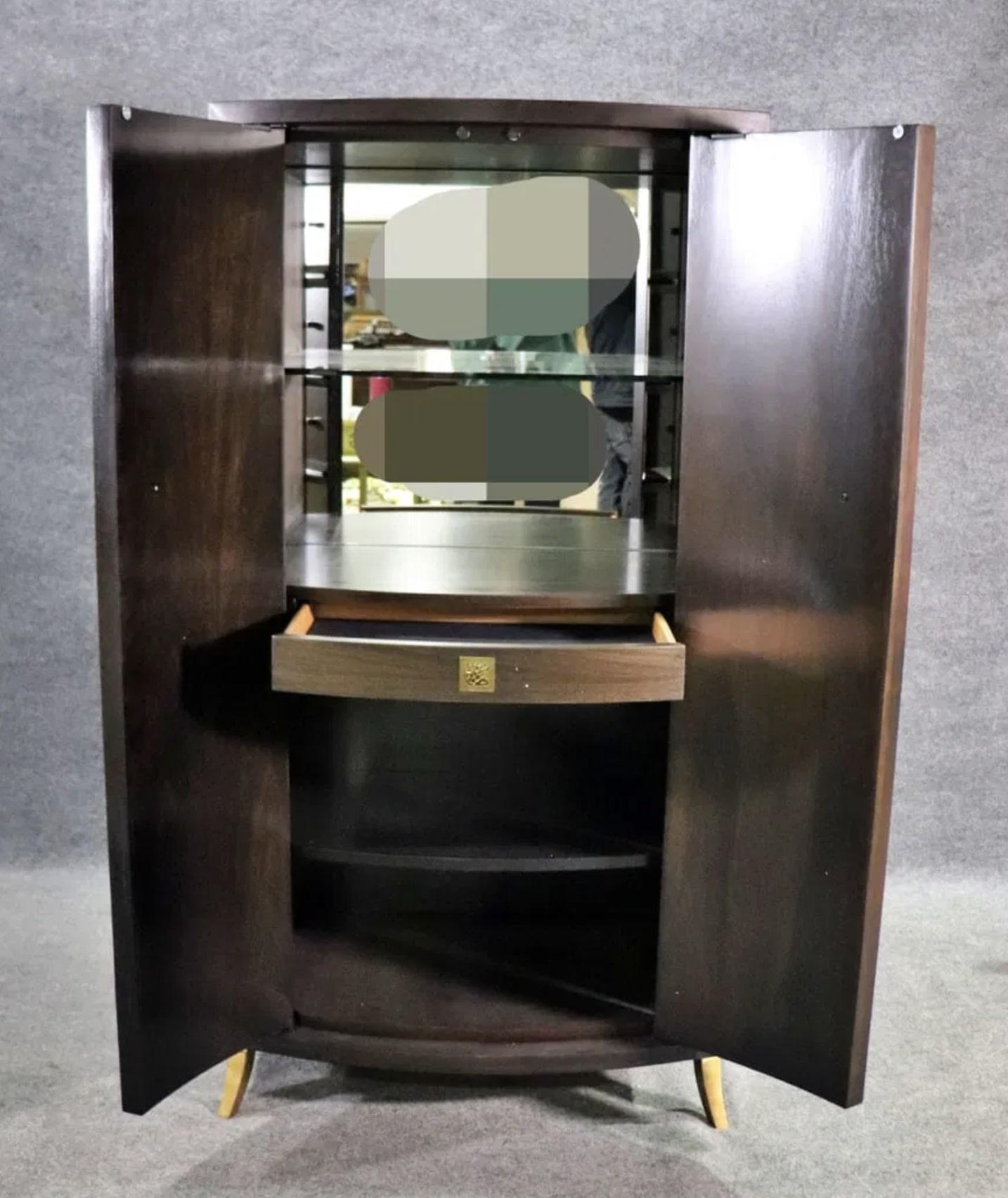 Grande armoire à deux portes de Baker avec intérieur dry bar. Les deux portes semblent être des tiroirs d'apothicaire avec des boutons en laiton, mais elles s'ouvrent sur un meuble ouvert avec un dos en miroir et une étagère extractible. 
2