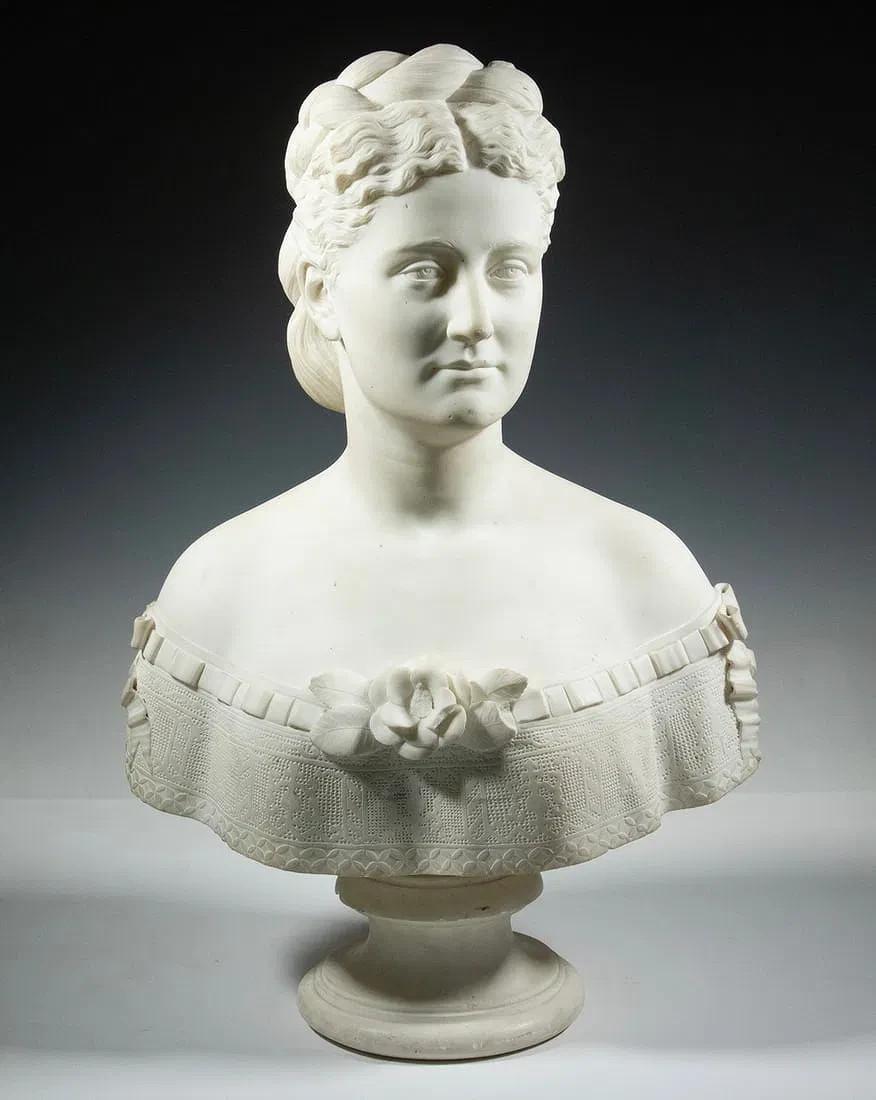 Ritratto vittoriano di una signora con capelli acconciati, corpetto scollato con nastri e fiori, marmo di Carrara, poggia su un piolo di ferro su un basamento separato. Firmato 