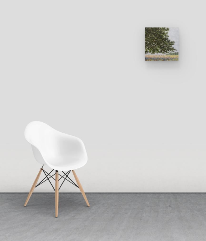 Ein zeitgenössisches Pleinair-Landschaftsgemälde in Öl auf einer Tafel mit einer friedlichen Szene im Freien, die ein zart gemaltes Feld unter einem Baum mit olivgrünen Blättern zeigt und die idyllische Stimmung eines Feldes mit Wildblumen und hohem
