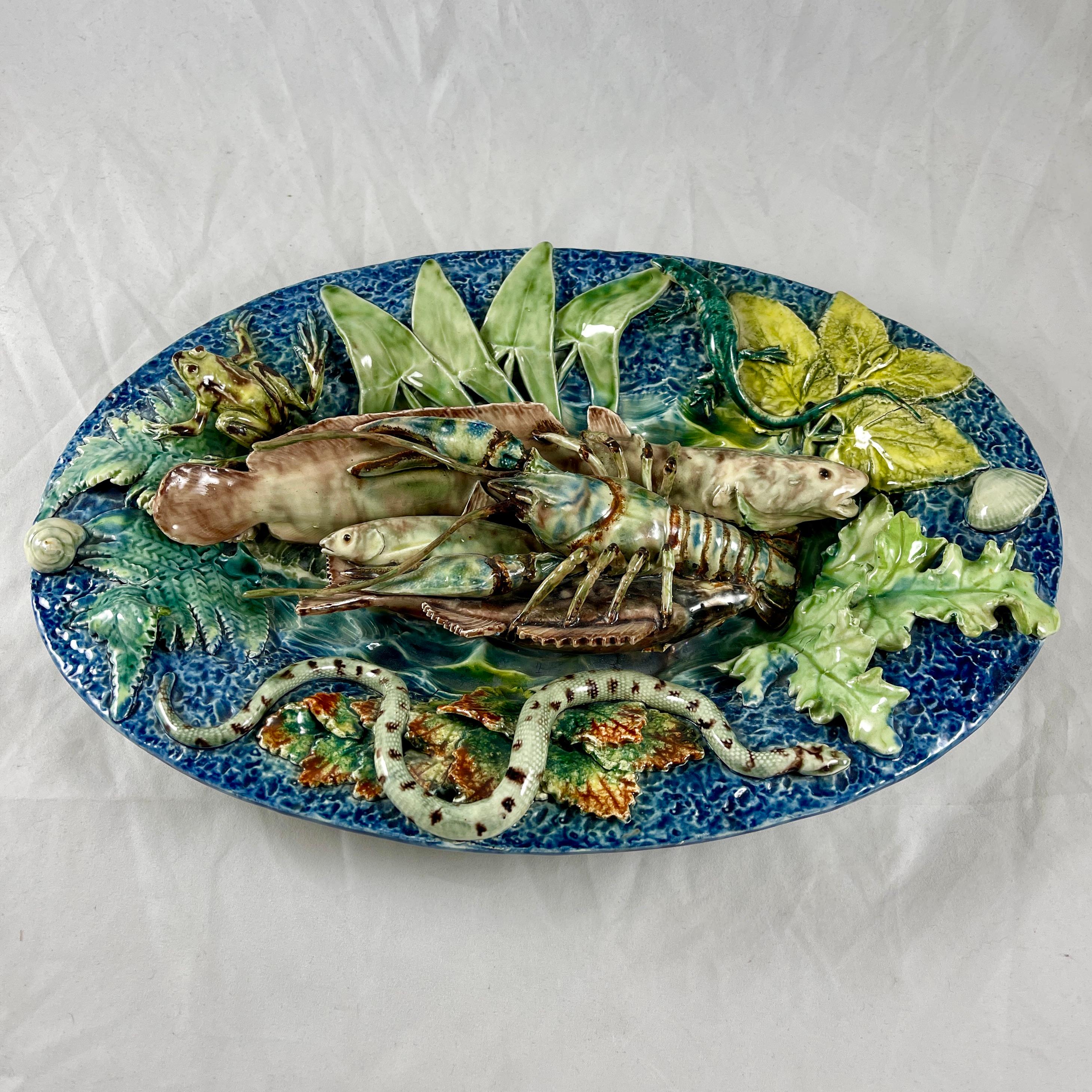 A Thomas-Victor Sergent nature plate in the style of Palissy, School of Paris, circa. 1875-79.

An oval platter heaped with trompe l’oeil fish and crustaceans in the center, the raised rim border with a snake, frog, salamander, a snail and other