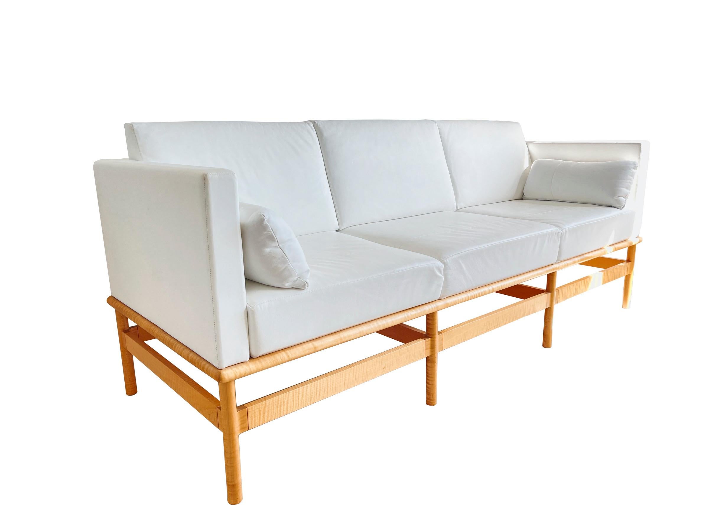 Custom Thos. Moser Hartford shelter arm sofa rendered in white leather upholstery with three removable loose back cushions and two lumbar pillows, supported by an architectural frame of hand crafted Fig Maple, designed and Manufactured by Thomas