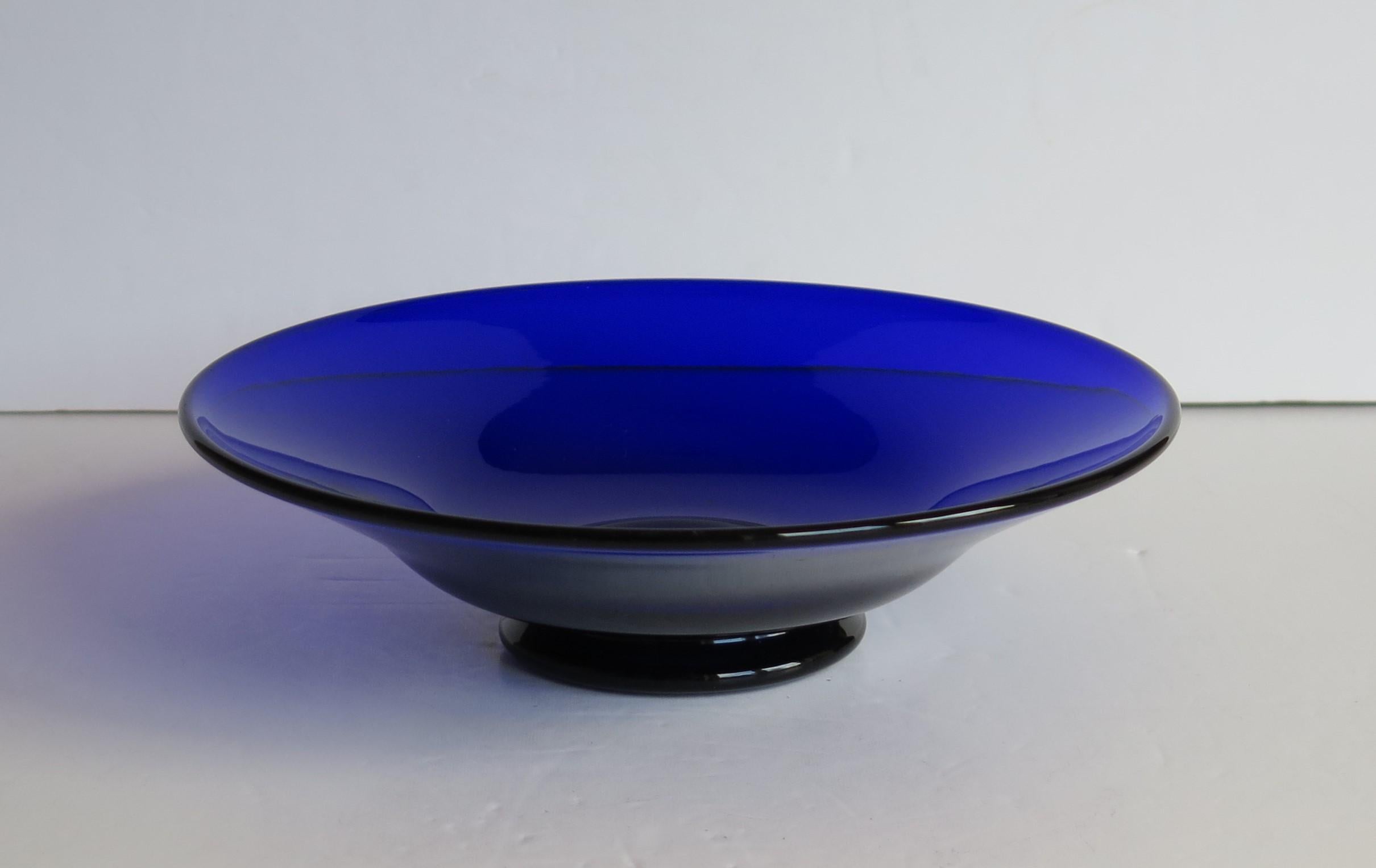 This is a fine quality glass bowl by the glass manufacturer Thomas Webb. 

This circular bowl is made of bristol or cobalt blue and has a lovely curved shape with a flared rim raised on a shaped foot. 

Thomas Webb was an English glassmaker and
