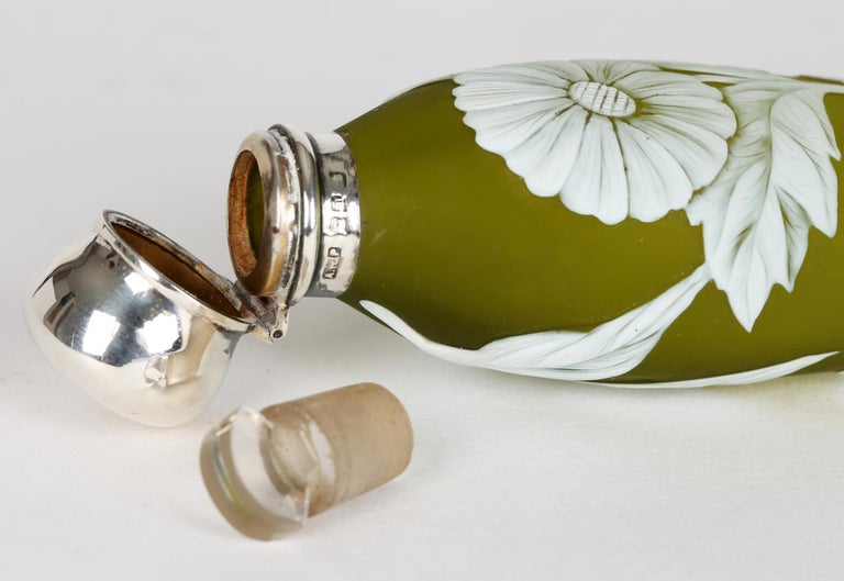 A stunning antique cameo green glass silver mounted scent bottle by Thomas Webb dating from around 1886. The bottle is of elongated flask or teardrop shape and has a white glass overlay on a satin olive green ground. The white has been cut to form