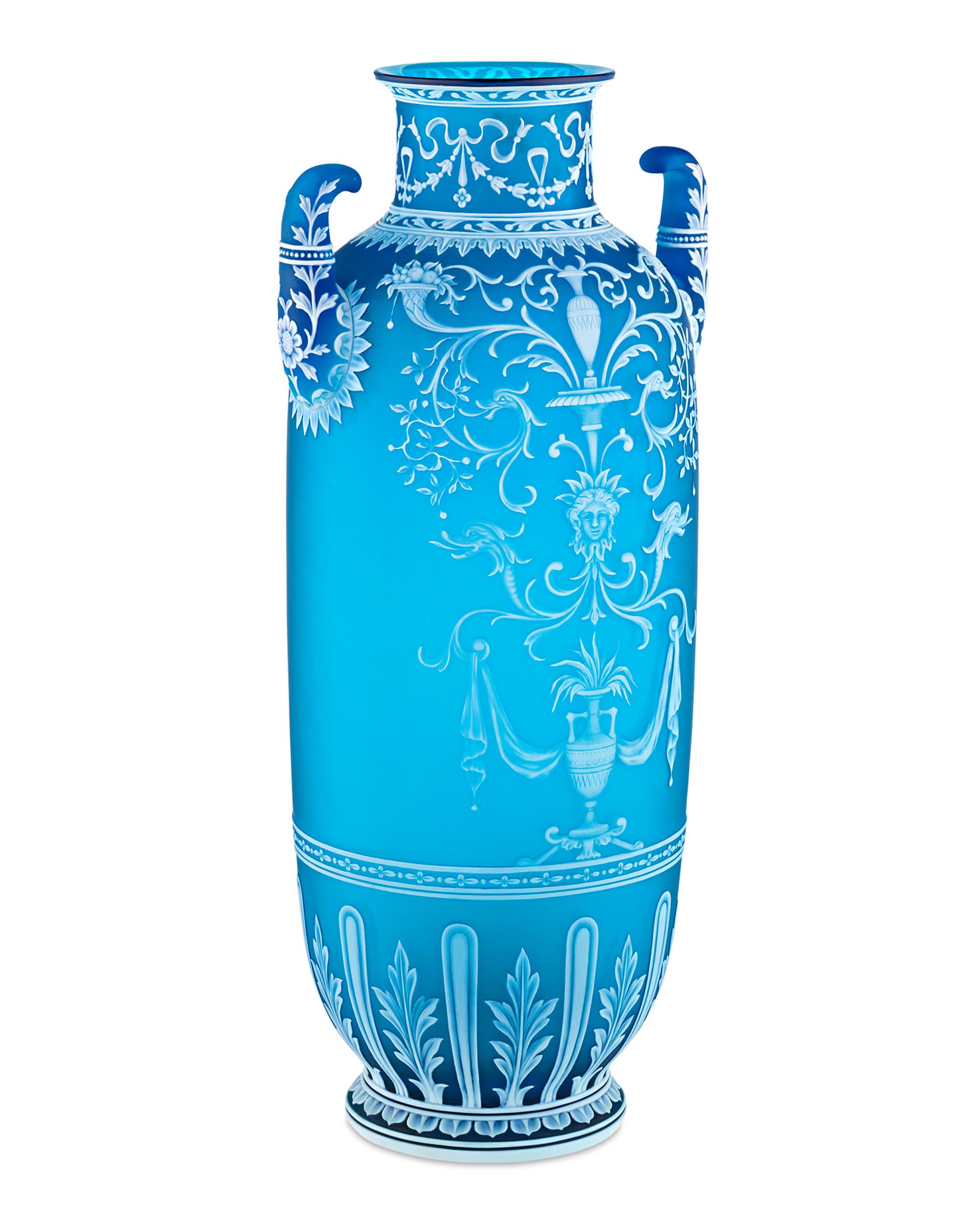 This rare and significant cameo glass vase exemplifies the exceptional craftsmanship of George Woodall, a master artist celebrated for his outstanding skill in cameo carving. The amphora-shaped vase stands tall, overlaid in opaque white and