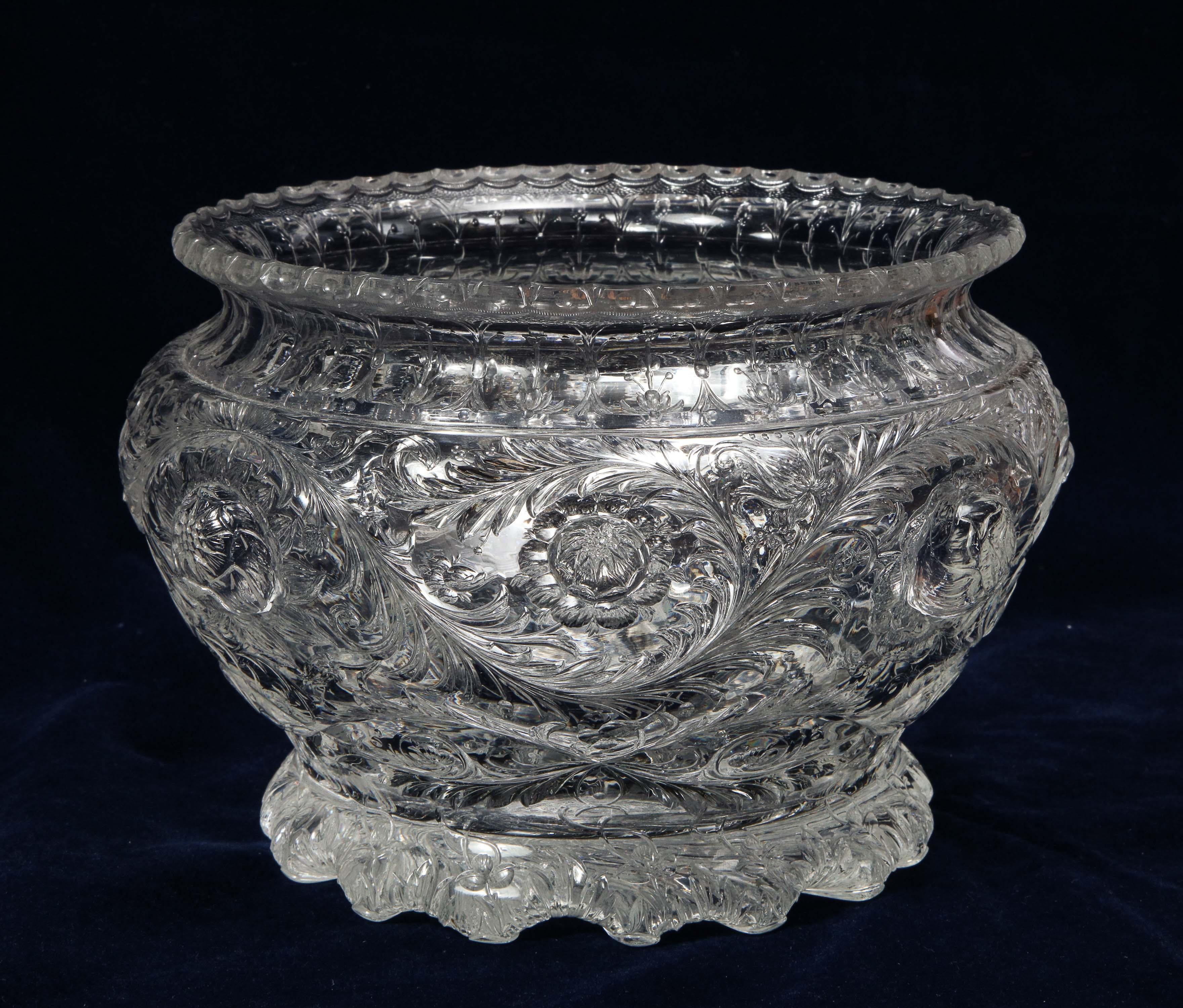A Rococo style Thomas Webb & Sons wheel carved 'Rock-Crystal’ type punch bowl/ centerpiece, circa 1890, designed by and signed Geo(rge) Woodall. Of tapering bulbous form, wheel-engraved and polished with scrolling vine centering large flower-heads