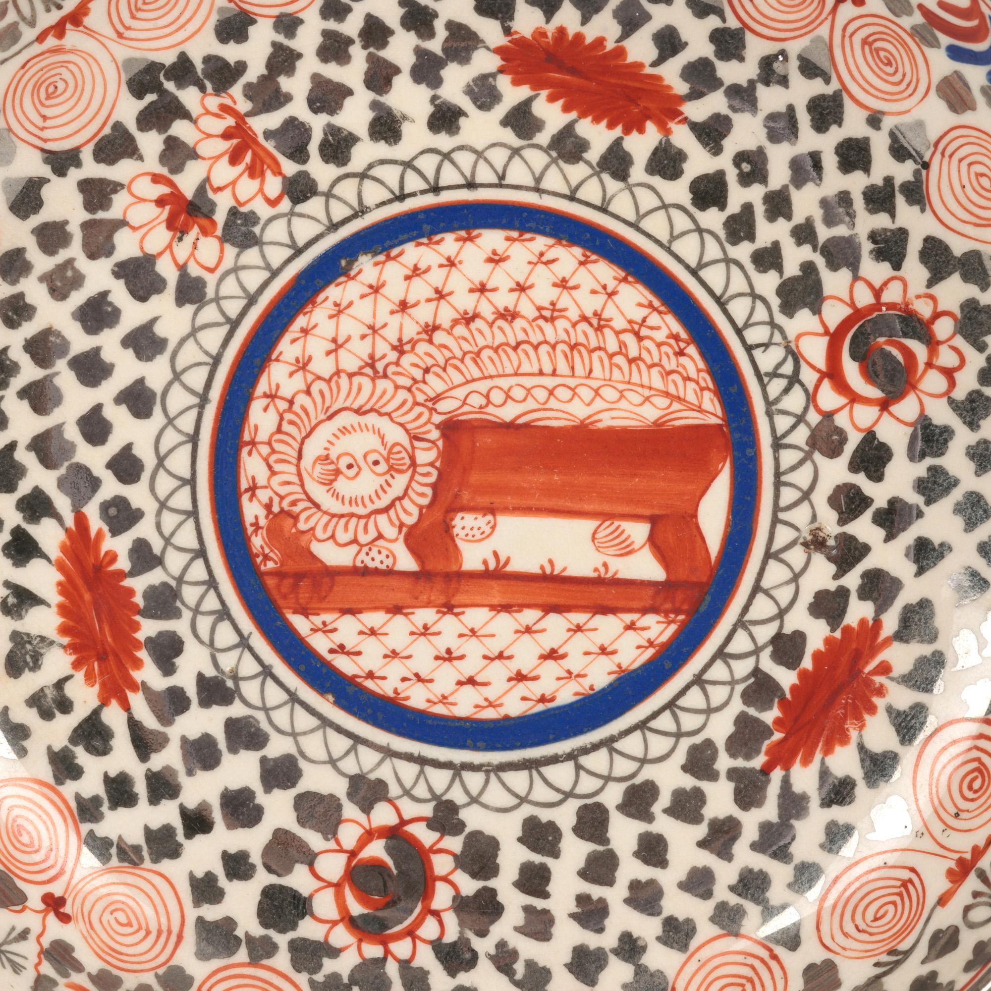 A scarce antique English Staffordshire bone china teacup and saucer hand decorated with a red lion by Thomas Wolfe (Factory Z) and dating from around 1810. The cup is of wide round shape with shaped side handle and is hand painted in tones of red