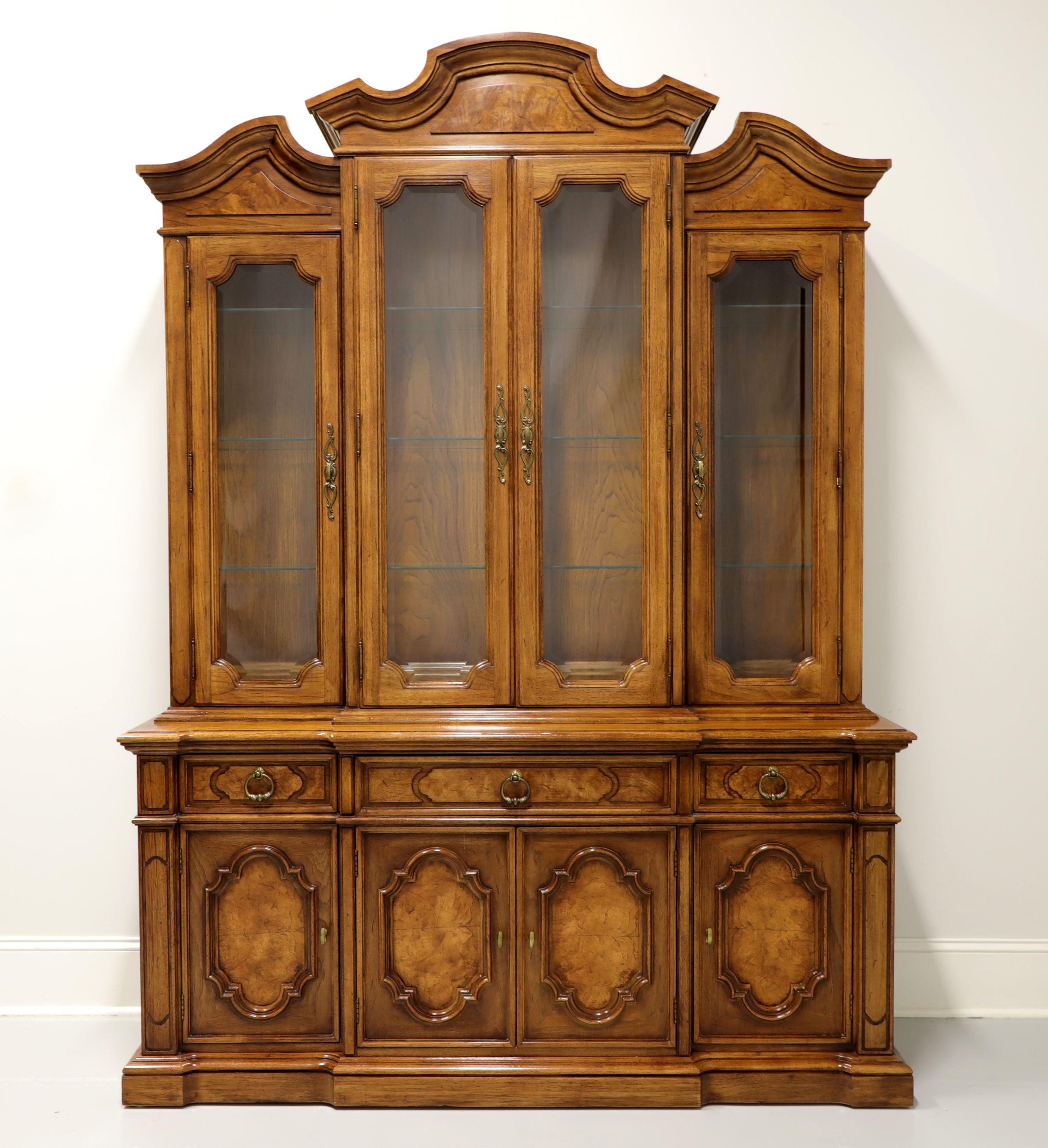 A Mediterranean style china cabinet by Thomasville, from their Ceremony Collection. Walnut with brass hardware, distinctive arched top with crown moulding and burl walnut inlays to top, drawer fronts & door fronts. Upper lighted cabinet has four