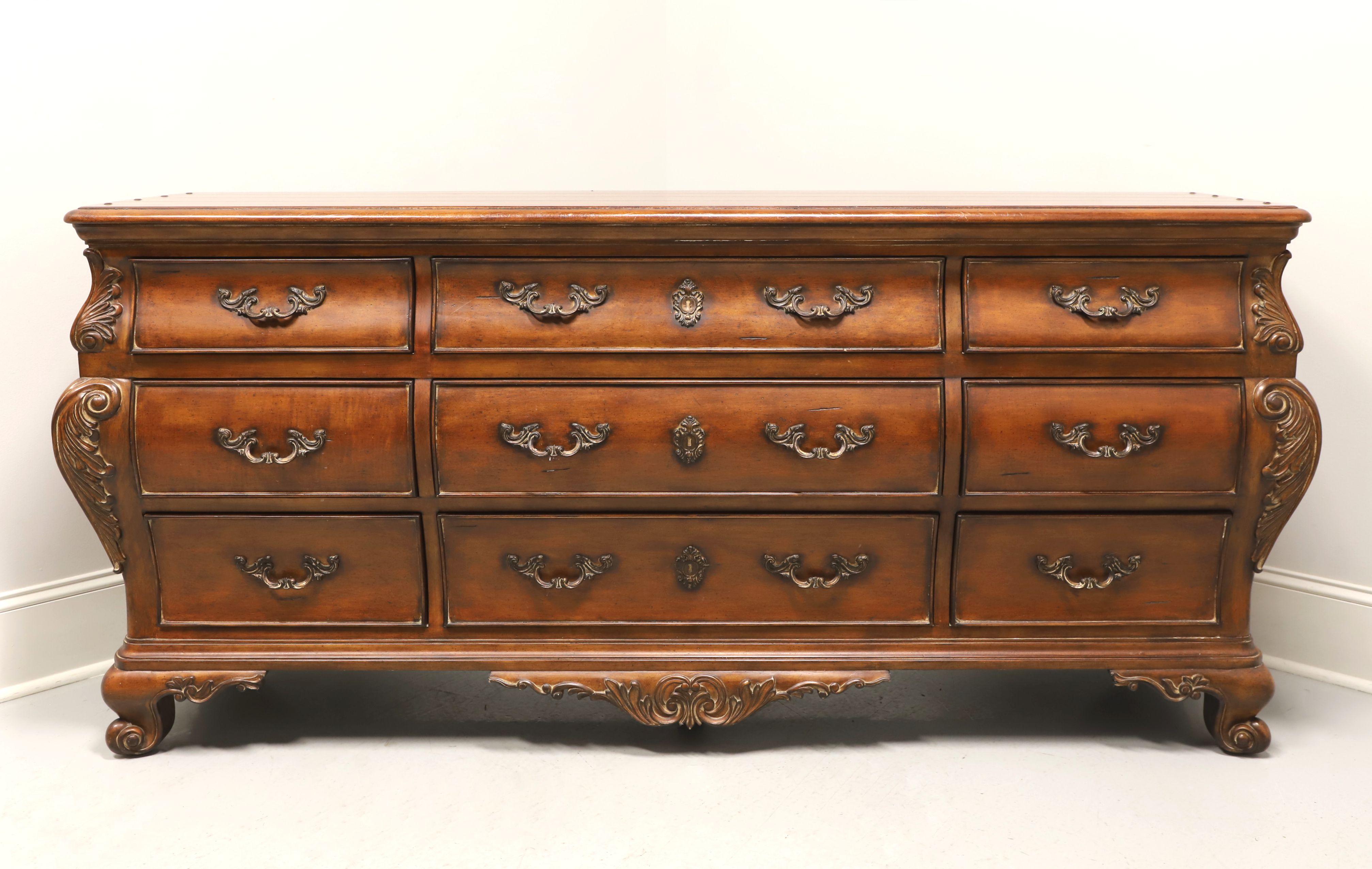 A triple dresser in the French Country style by Thomasville, from their Chateau Provence Collection. Walnut with plank like top, brass hardware, a slightly distressed finish, decoratively carved contoured sides with acanthus leaves, carved apron