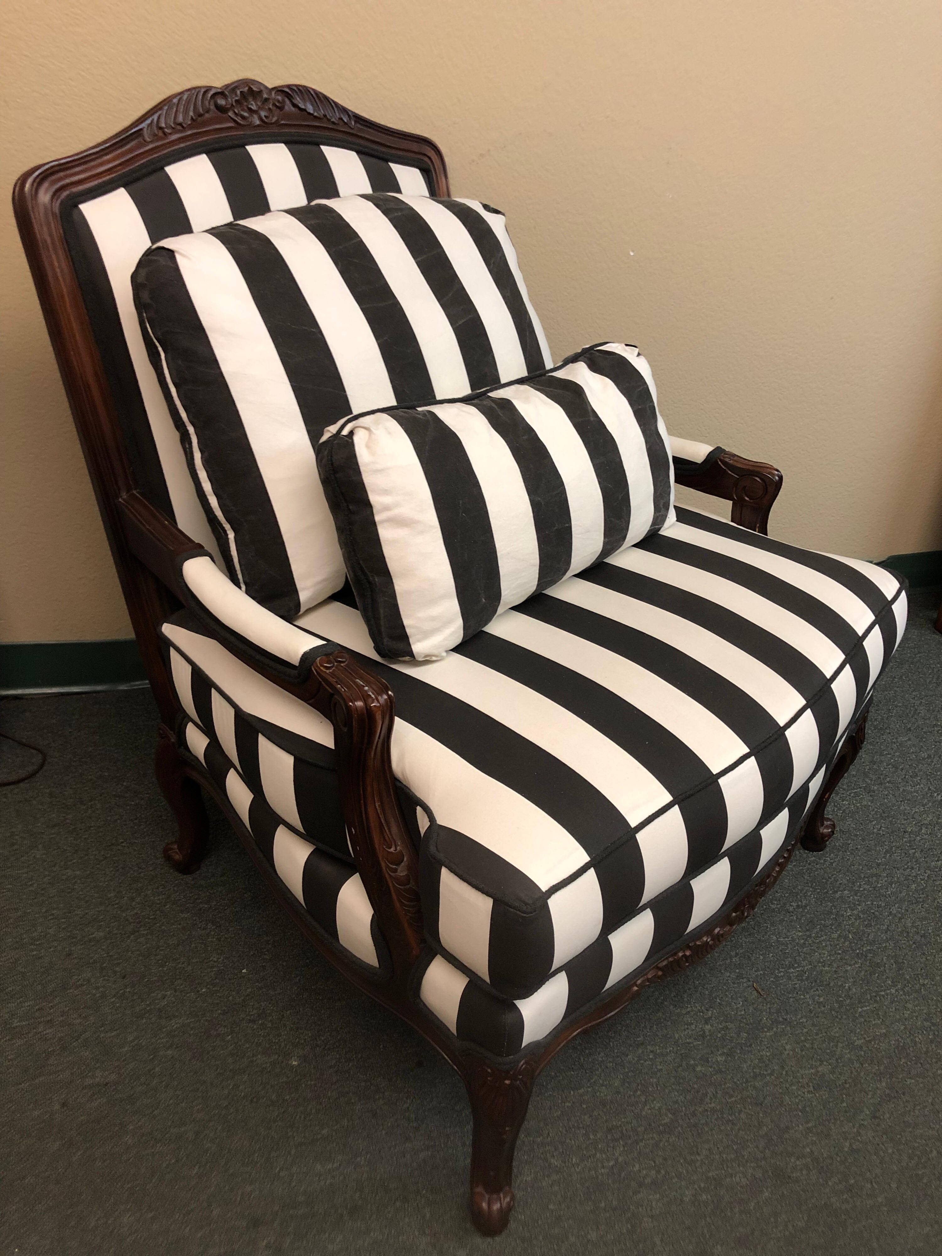 A Fauteuil style armchair by Thomasville Furniture. Upholstered in a vertical black & white color stripe fabric. One loose seat and back cushion, accompanied with a matching lombard pillow. The exposed carved wood frame is in mahogany finish. Arm