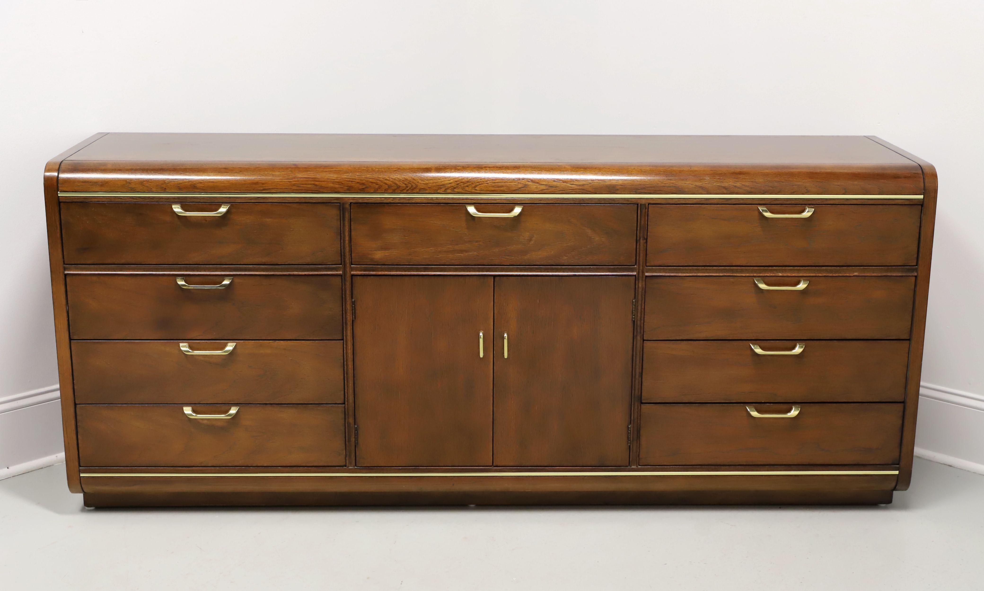 A Post-Modern style triple dresser by Thomasville, from their Founders Collection. Walnut with brass hardware & accents, waterfall edges, and on a slightly recessed solid base. Features twelve drawers of dovetail construction, three of which are