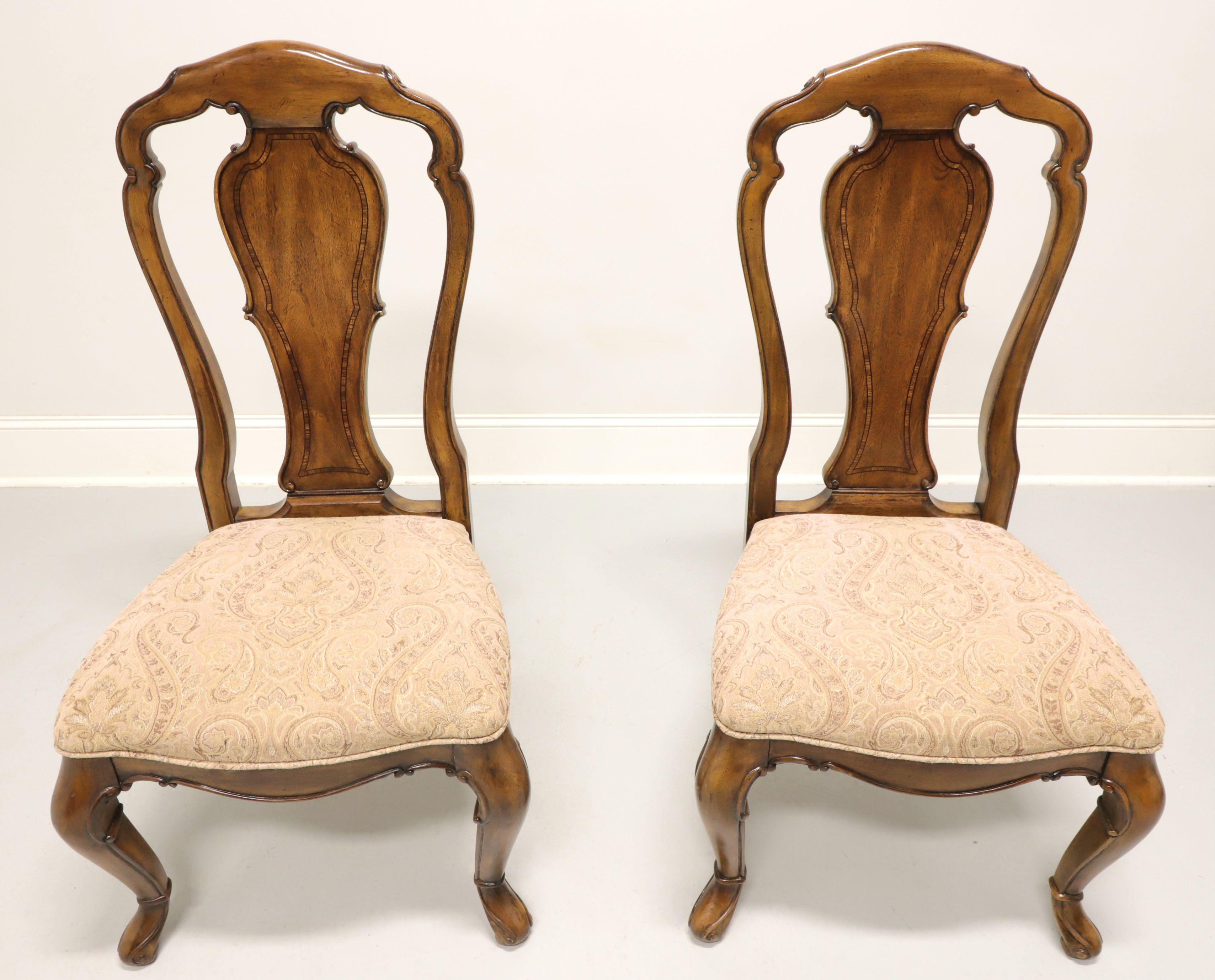 A pair of Spanish Mediterranean style dining side chairs by Thomasville, their Granada from the Ernest Hemingway Collection. Mahogany with carved crestrail, fiddle backrest, pink/beige/brown paisley pattern fabric upholstered seats, carved apron,