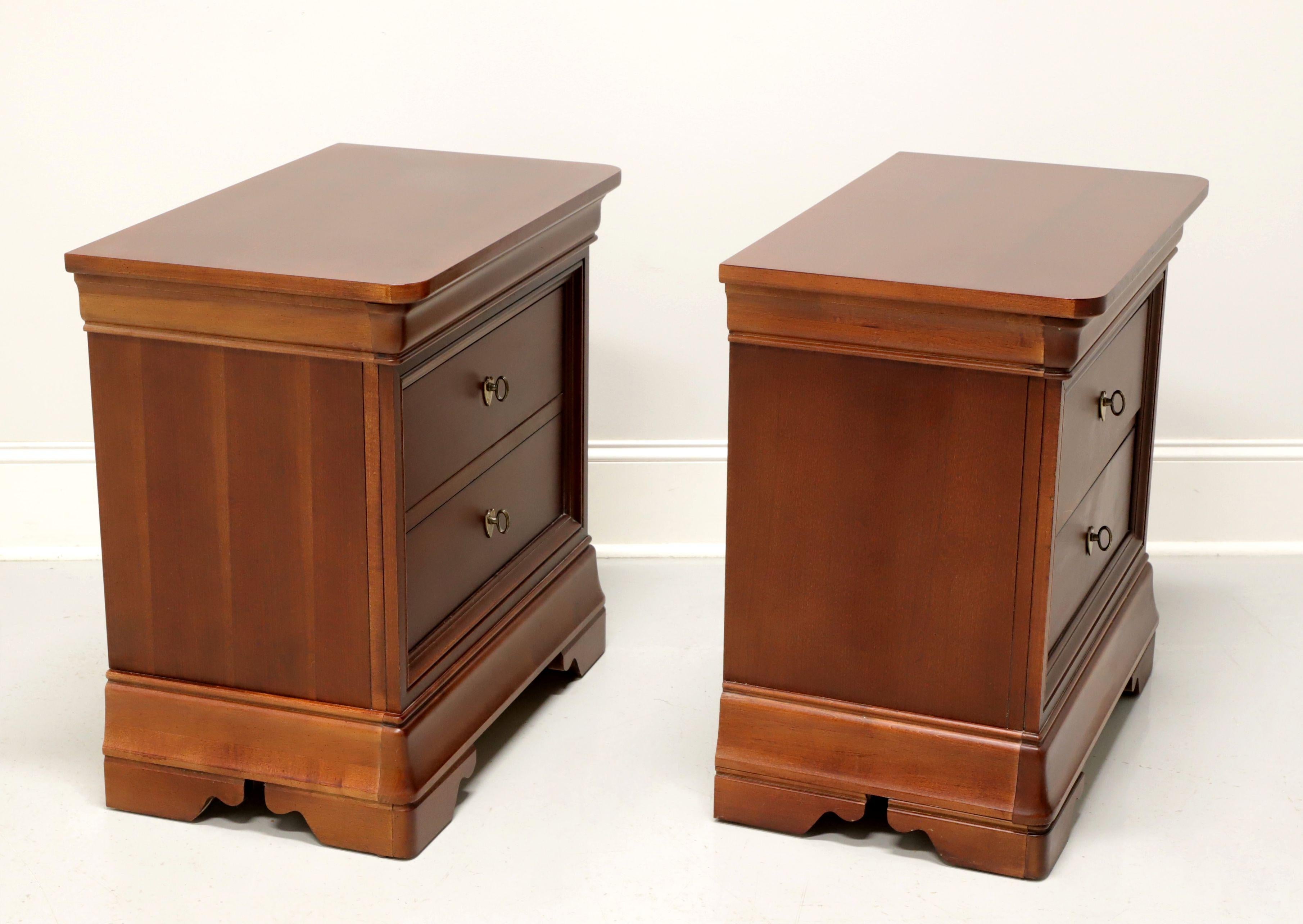 A pair of French Louis Philippe style nightstands by Thomasville, from their Impressions Martinique Collection. Cherry wood with their Merlot finish, brass hardware, rounded corners to top and bracket feet. Features two drawers of dovetail