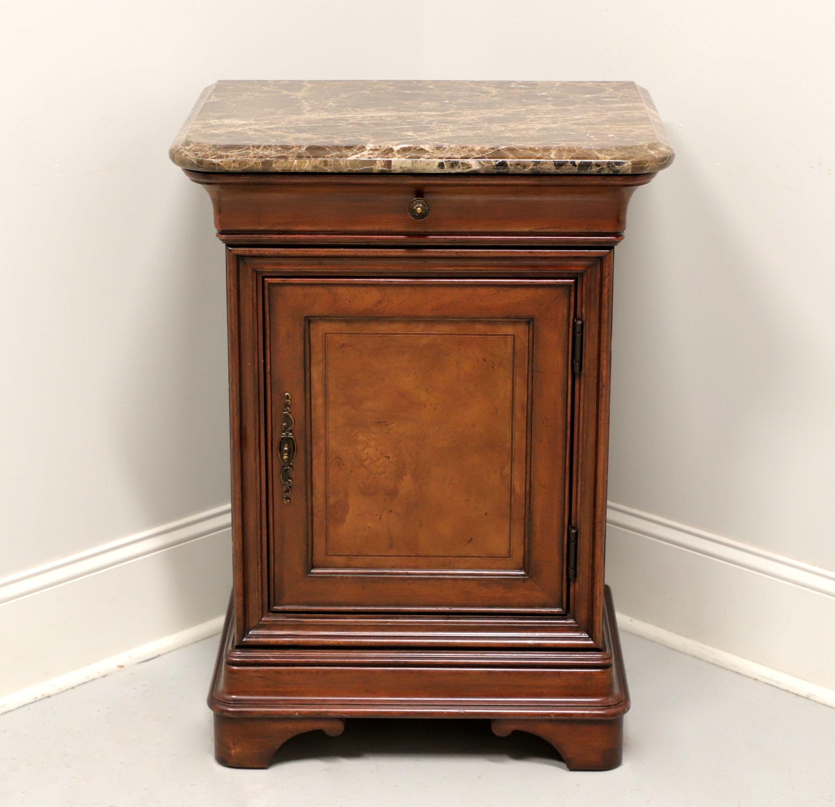 A Transitional style bedside cabinet by Thomasville. Elm with inlaid burl elm to door front, brass hardware, cultured marble top and bracket feet. Features one drawer concealed in the upper moulding over a single door lower cabinet revealing storage