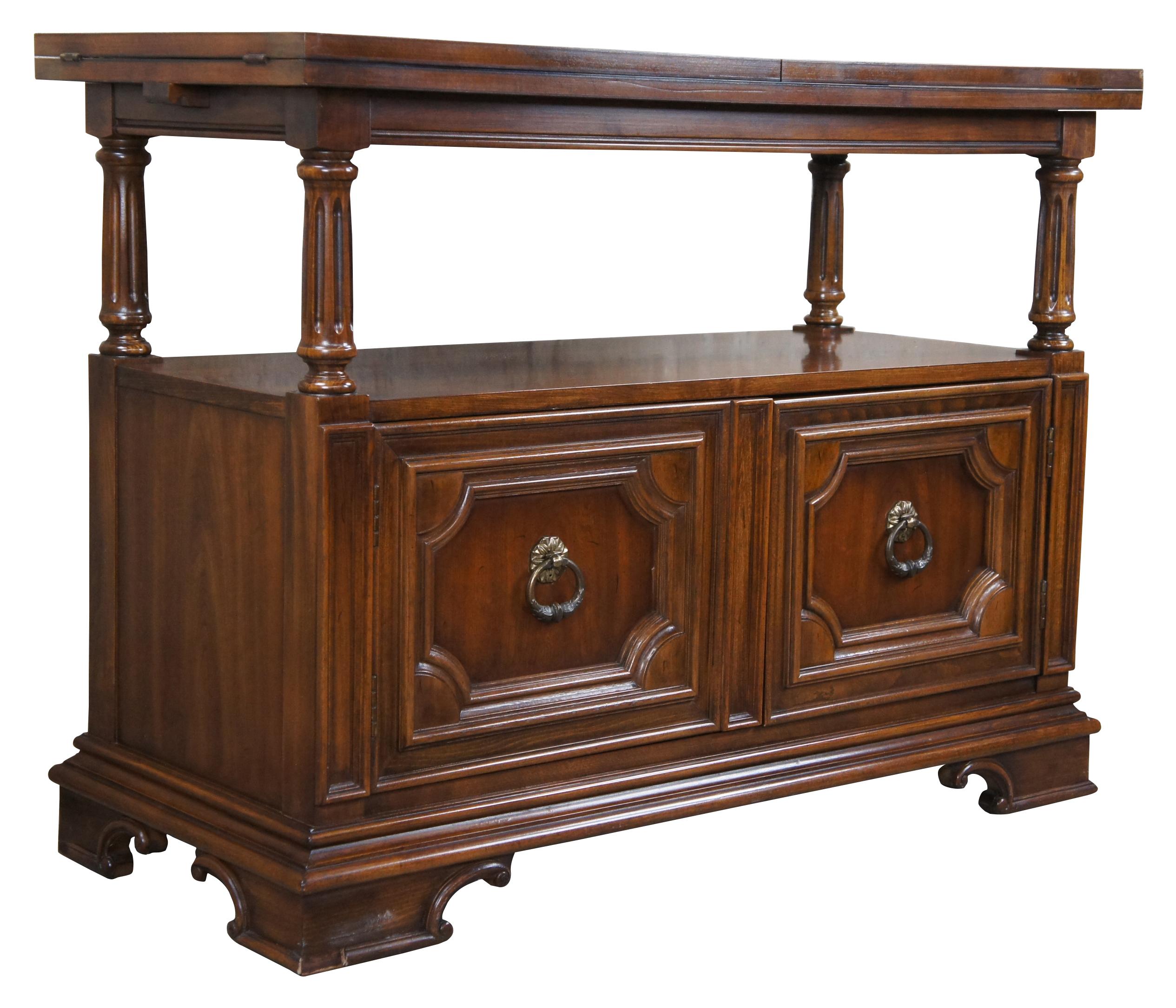 Thomasville traditional flip top server, circa 1980s. A rectangular form featuring an open center supported by turned and fluted columns. The lower cabinet is accented by inset molding and knocker pulls. When open, the top has a sleek black Formica