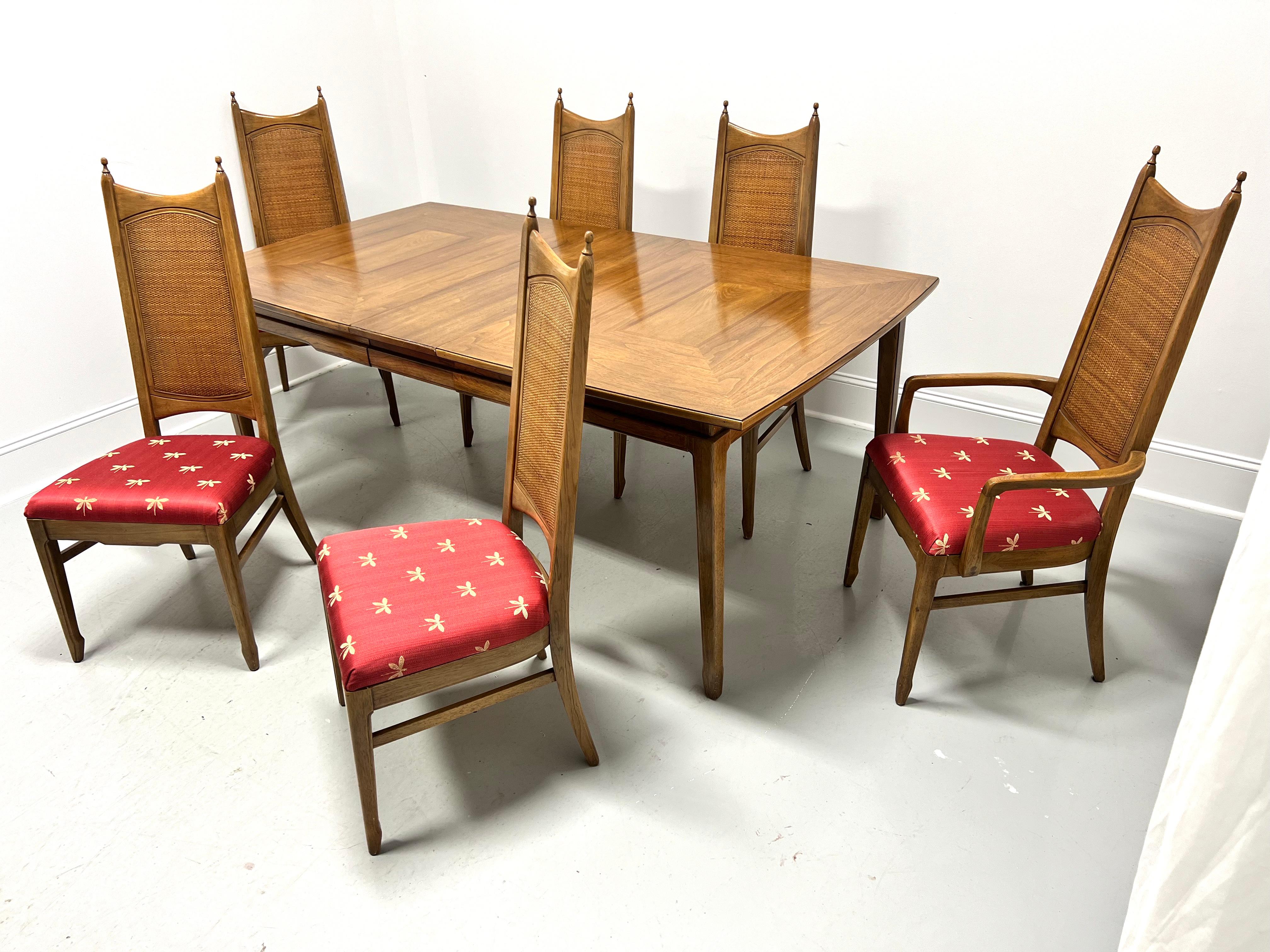 A Mid 20th Century Modern dining set by Thomasville. Made from pecan, or a similar nutwood. Dining table has an inlaid geometric pattern top with a bevel edge, carved apron, tapered straight legs, and spade feet. Includes one 12 inch extension leaf