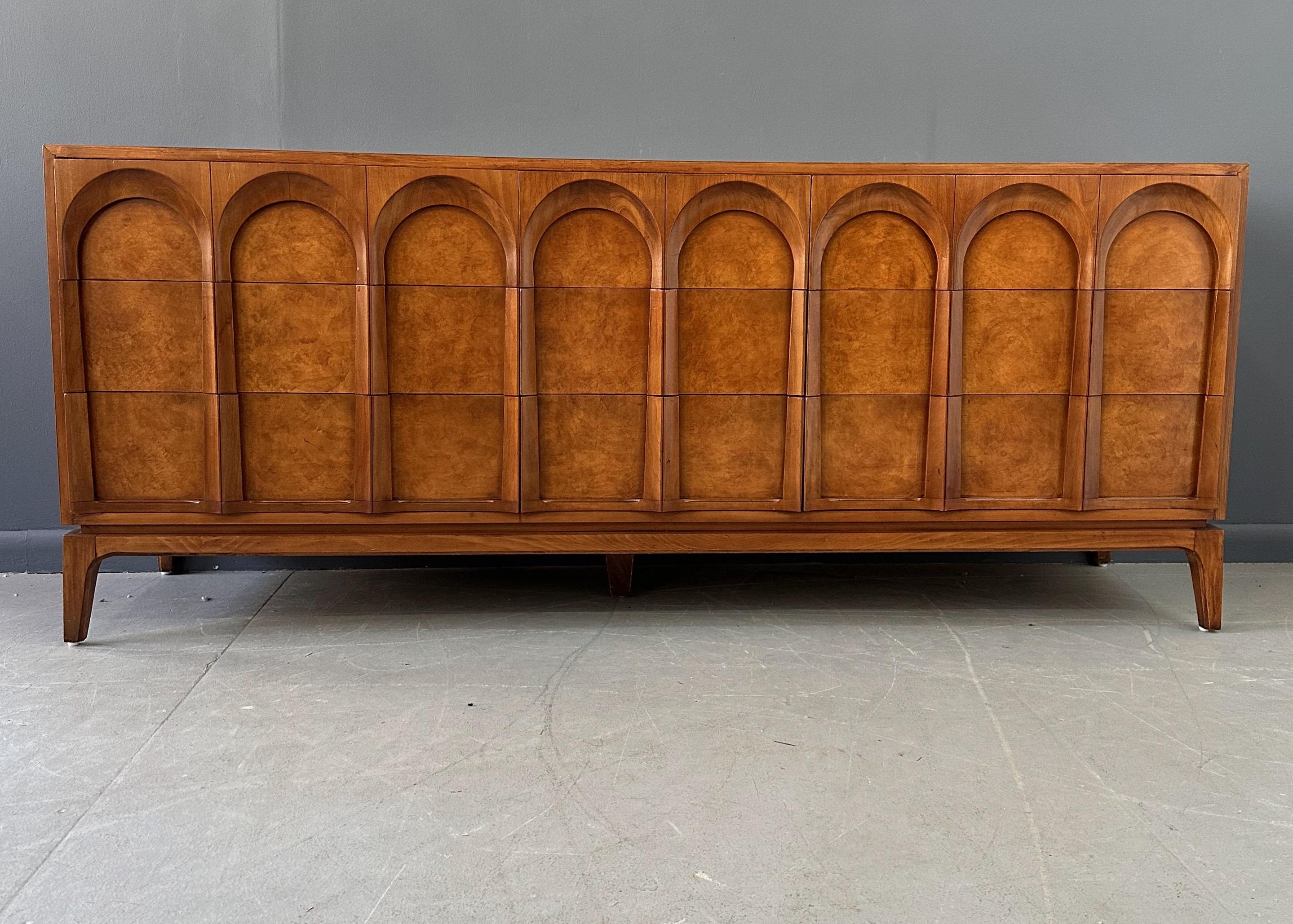 In the classic and timeless style of T.H. Robsjohn Gibbings, the 'Arched' series by Thomasville is made in the US, circa 1960s, and is of heirloom quality. The finest hardwoods of walnut and olive ash burl, create a sculptural rhythm that evokes