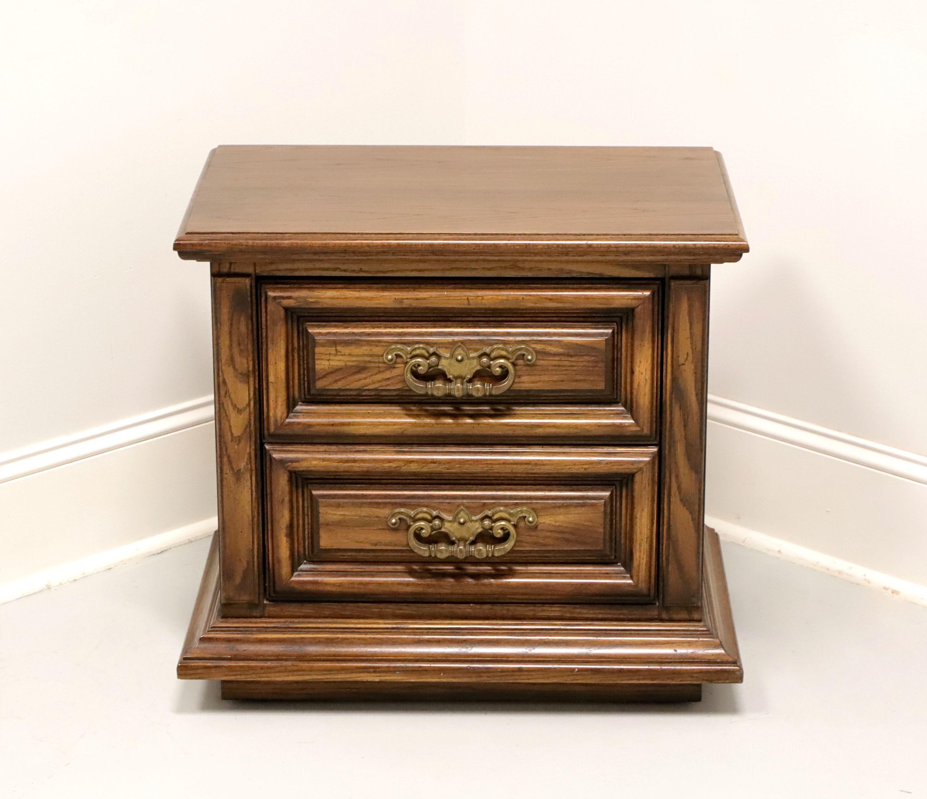 A Spanish Mediterranean style nightstand by Thomasville, from their Segovia Collection. Solid oak with slightly distressed finish, bevel edge top, brass hardware, raised drawer fronts, and a solid base. Features two drawers of dovetail construction.