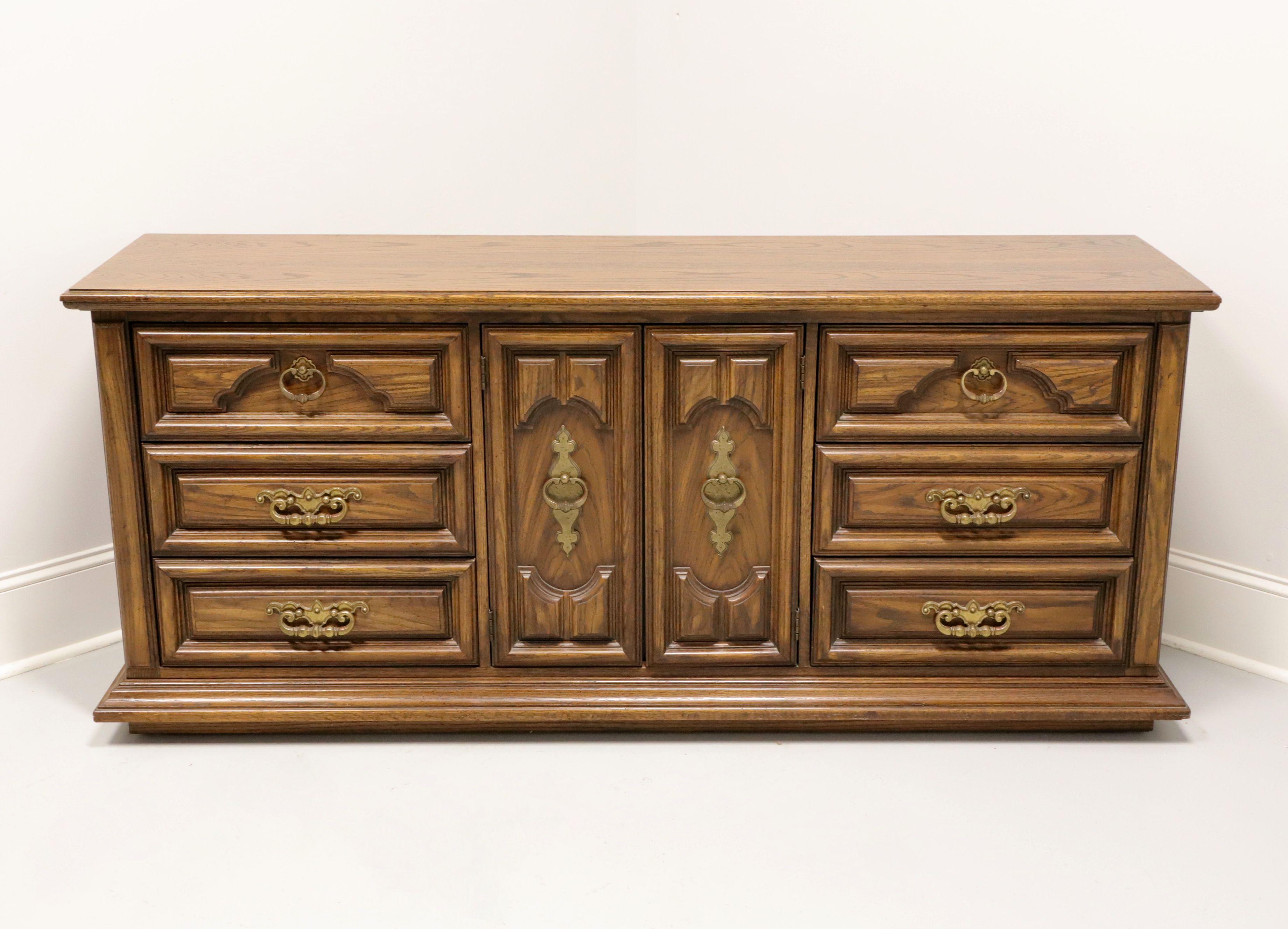 A Spanish Mediterranean style triple dresser by Thomasville, from their Segovia Collection. Solid oak with slightly distressed finish, bevel edge top, brass hardware, raised door & drawer fronts, and a solid base. Features nine drawers of dovetail