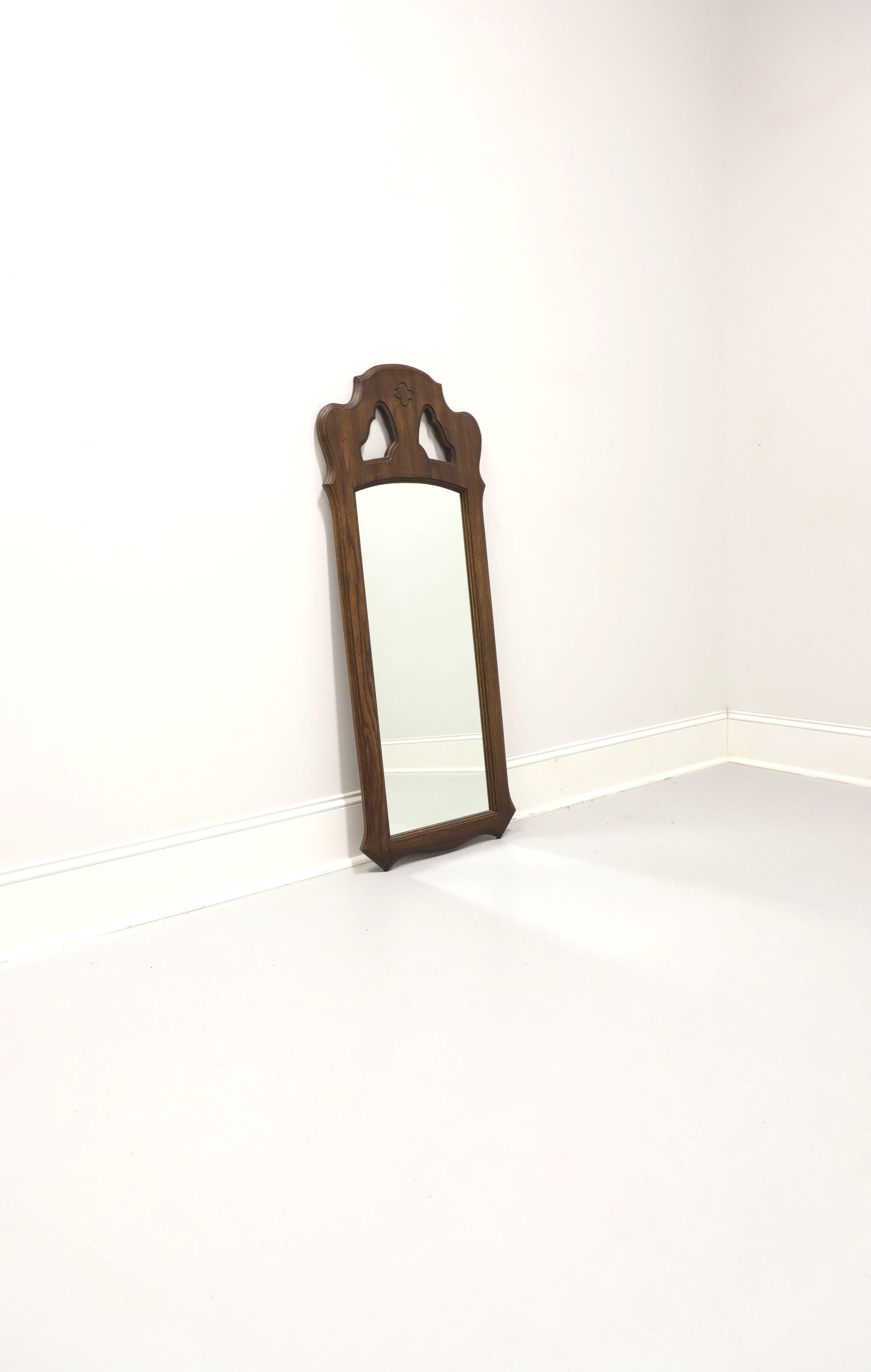 A Spanish Mediterranean style wall mirror by Stroupe Mirror, a division of Thomasville Furniture, from their Segovia Collection. Mirror glass in a solid oak frame with a slightly distressed finish, decoratively carved shape, and open carved area at