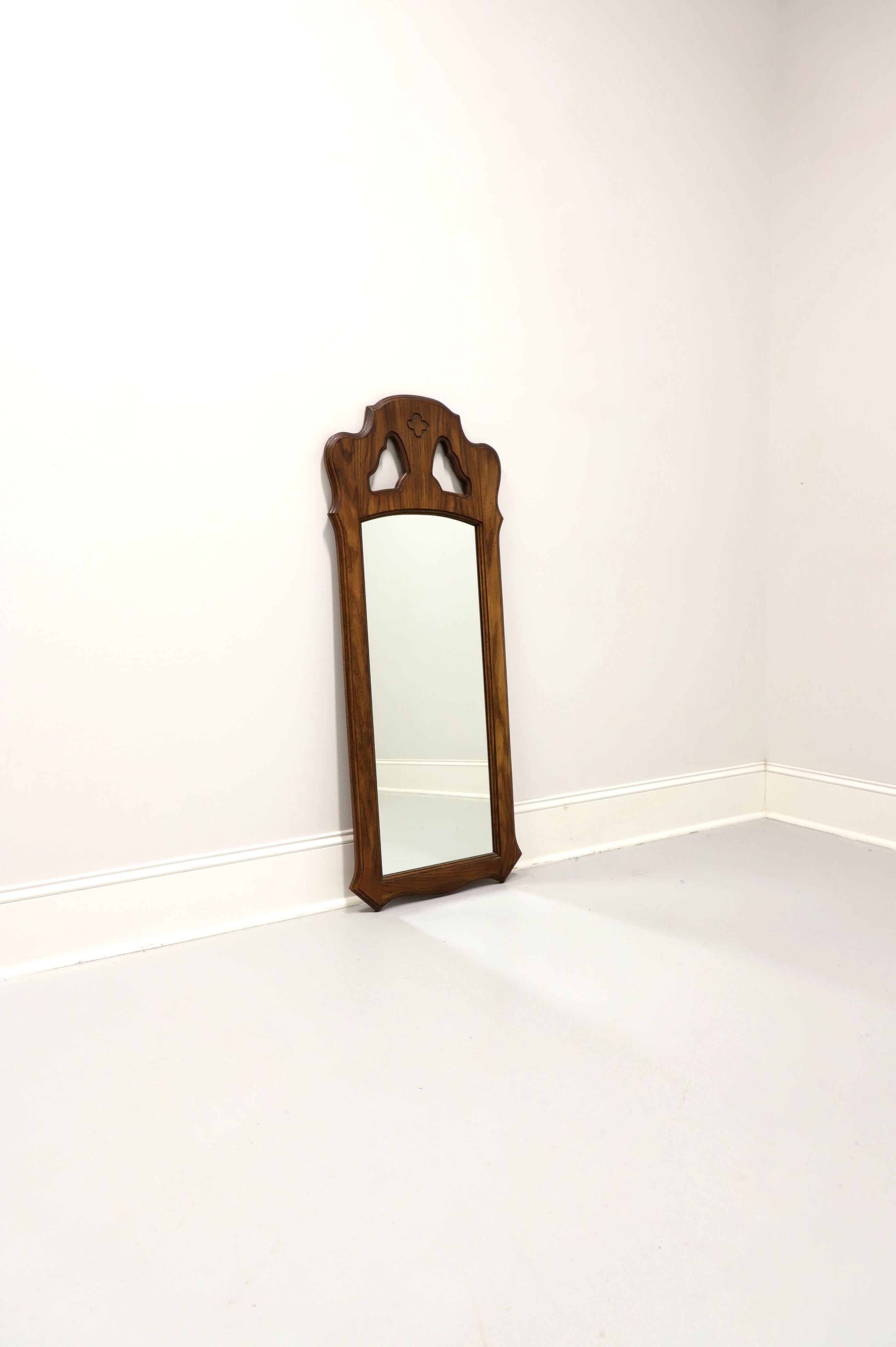 A Spanish Mediterranean style wall mirror by Stroupe Mirror, a division of Thomasville Furniture, from their Segovia Collection. Mirror glass in a solid oak frame with a slightly distressed finish, decoratively carved shape, and open carved area at