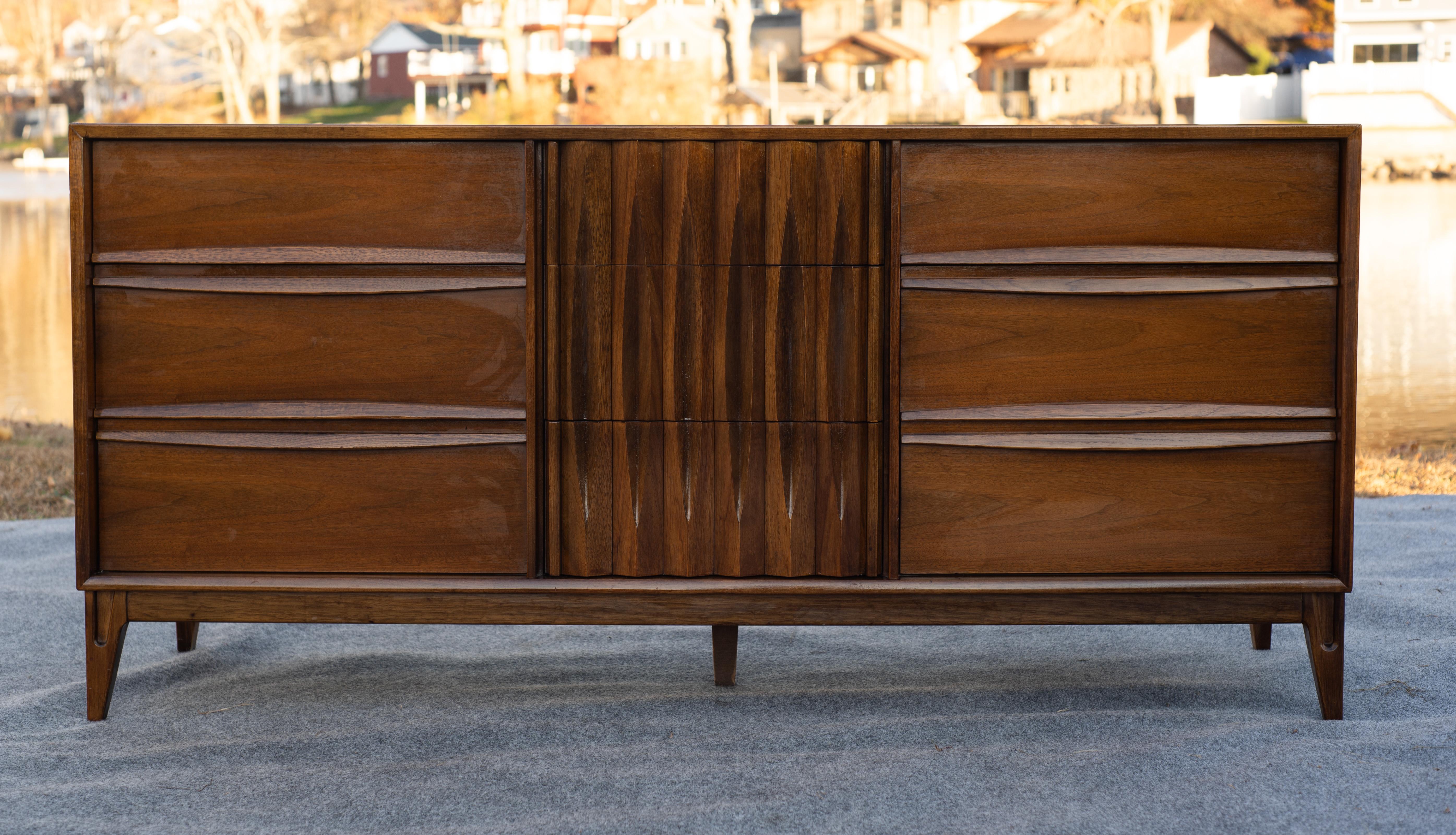 Progettato e realizzato negli Stati Uniti, questo comò/specchio è caratterizzato da un look eccellente e da una costruzione di alta qualità in noce, tipica del Mid-Century. Ogni segmento ospita tre grandi cassetti con struttura a coda di rondine e