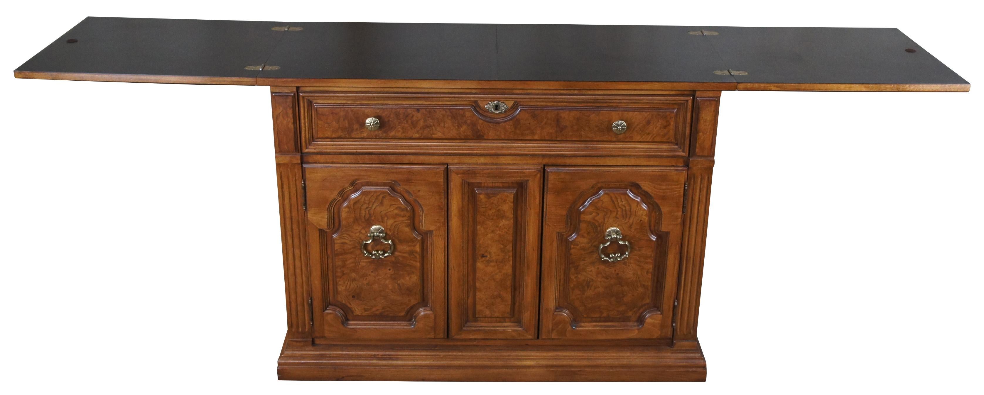 Thomasville buffet or server, circa 1970s. Made from walnut with olive ash wood burled panels. Includes a large upper dovetailed drawer and lower cabinet with shelf for storage. Upper surface butterflies open to a protective laminate top. On wheels