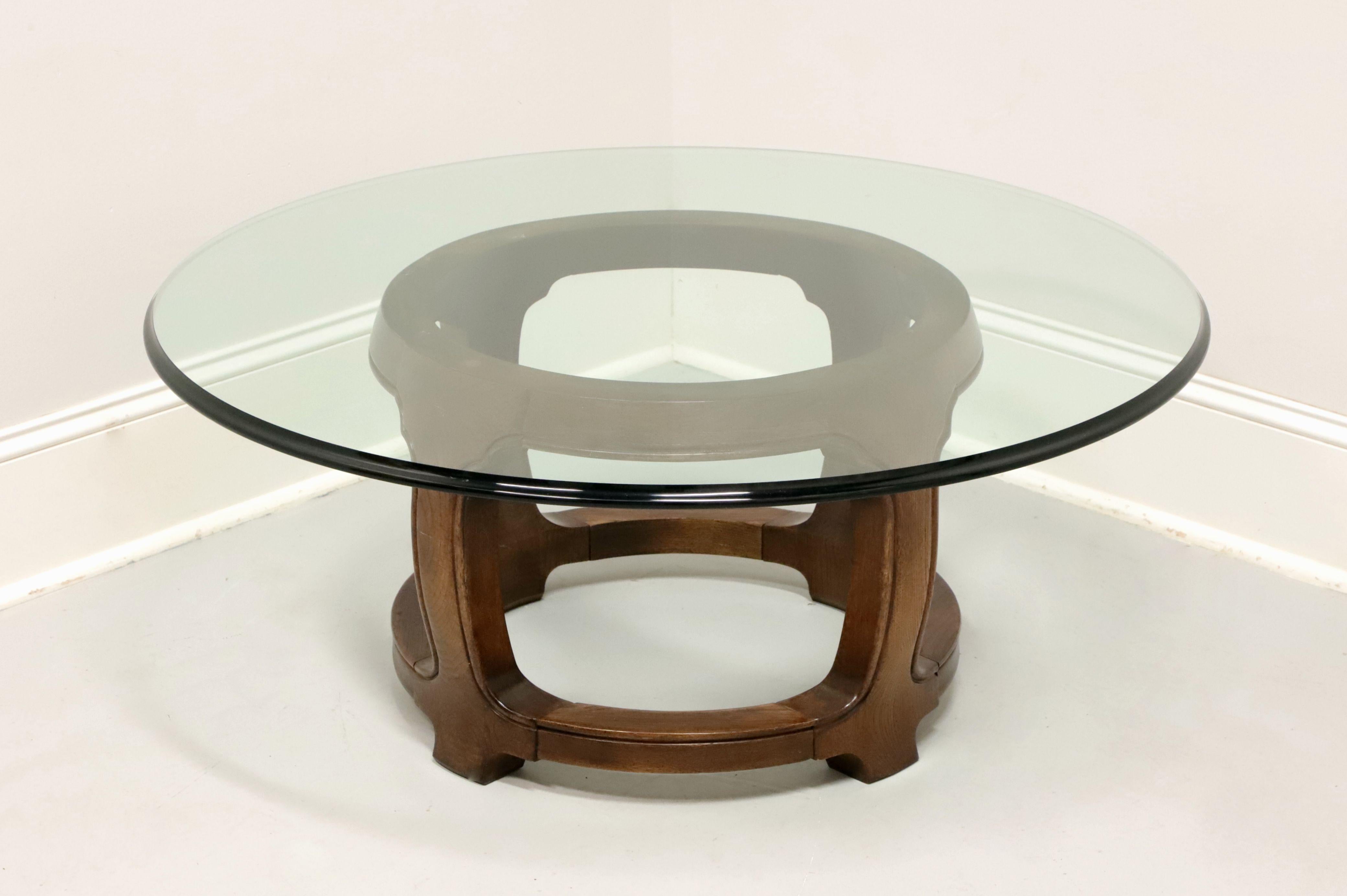 An Asian inspired cocktail table by Thomasville. Solid walnut in a round shape providing support for the ogee edge glass top. Made in North Carolina, USA, in the late 20th century.

Style #: 5531-170

Measures: Overall: 39.5w 39.5d 16.25h,